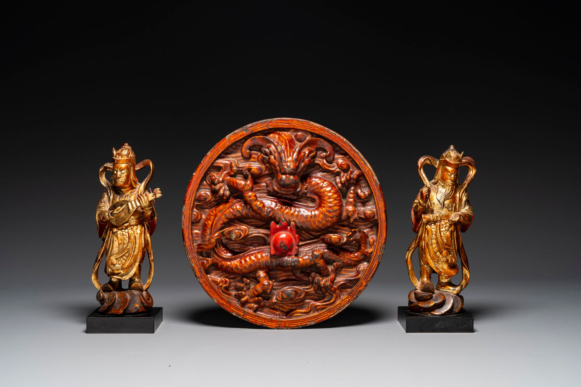 A pair of Chinese gilt-lacquered wooden guardians and a round 'dragon' plaque, 1&hellip;