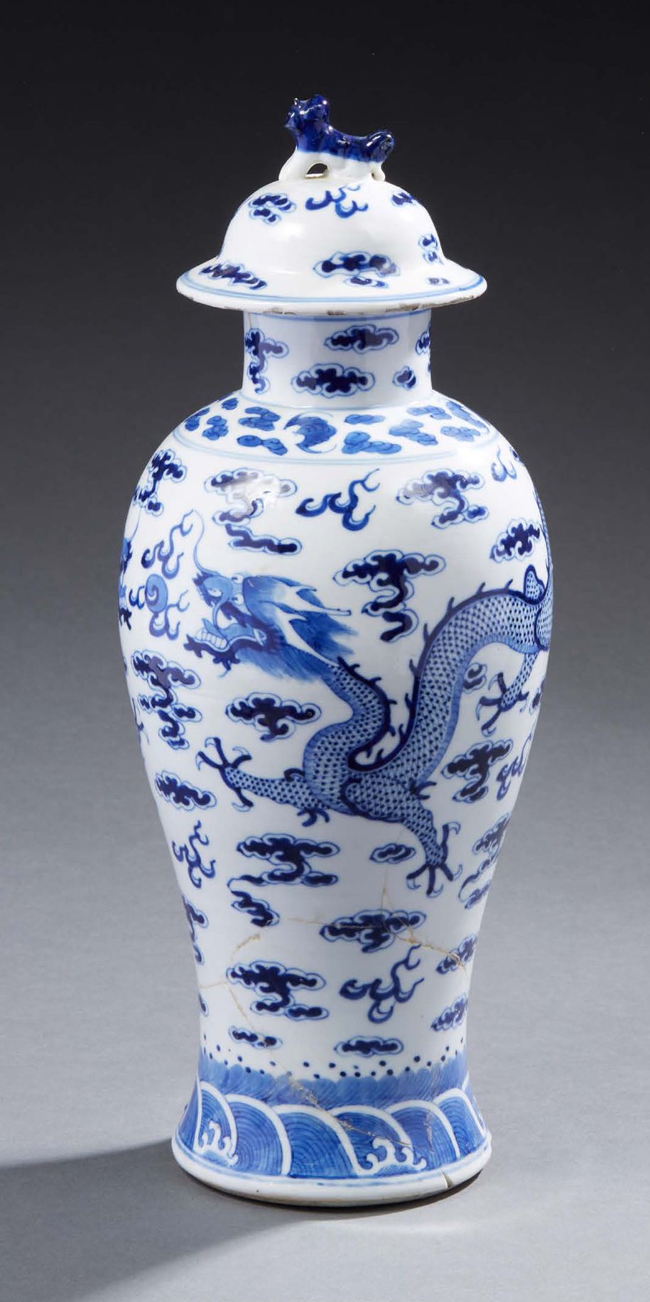 CHINE 
瓷盖花瓶，釉下蓝色装饰有一条在云中寻找圣珠的龙。
19世纪
高：39厘米
 （已破损并粘上）。