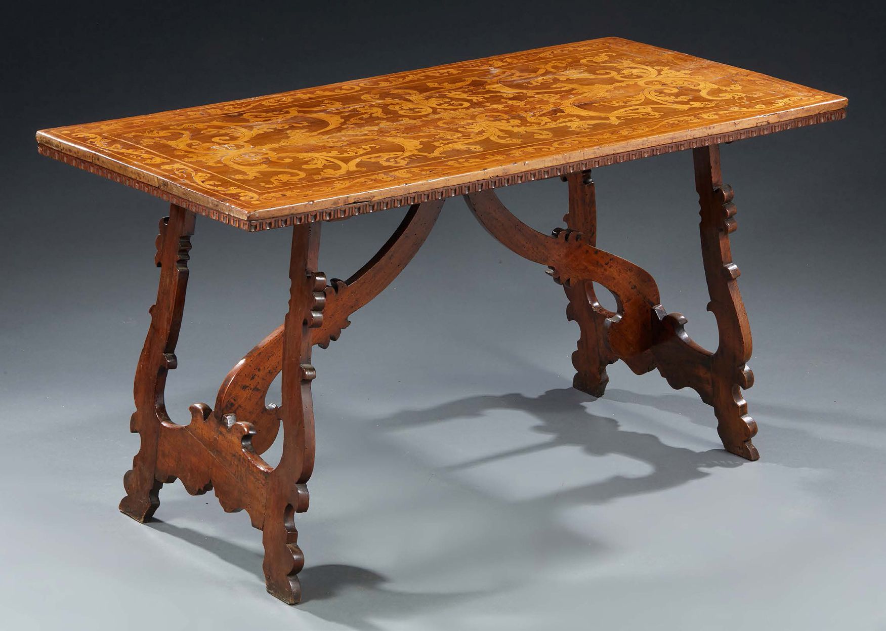 Null A walnut table, carved or sculpted; the top in intarsia with large scrolls,&hellip;