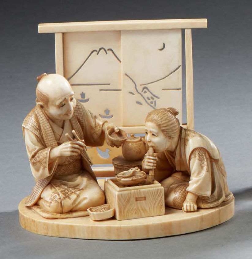 JAPON 象牙雕刻的和服表现了两个坐在茶道上的人物，一个人拿着筷子和碗，一个人对着余烬吹气。在他们身后，是一个有两块面板的可移动屏幕。背面签名为红色方块中的两&hellip;