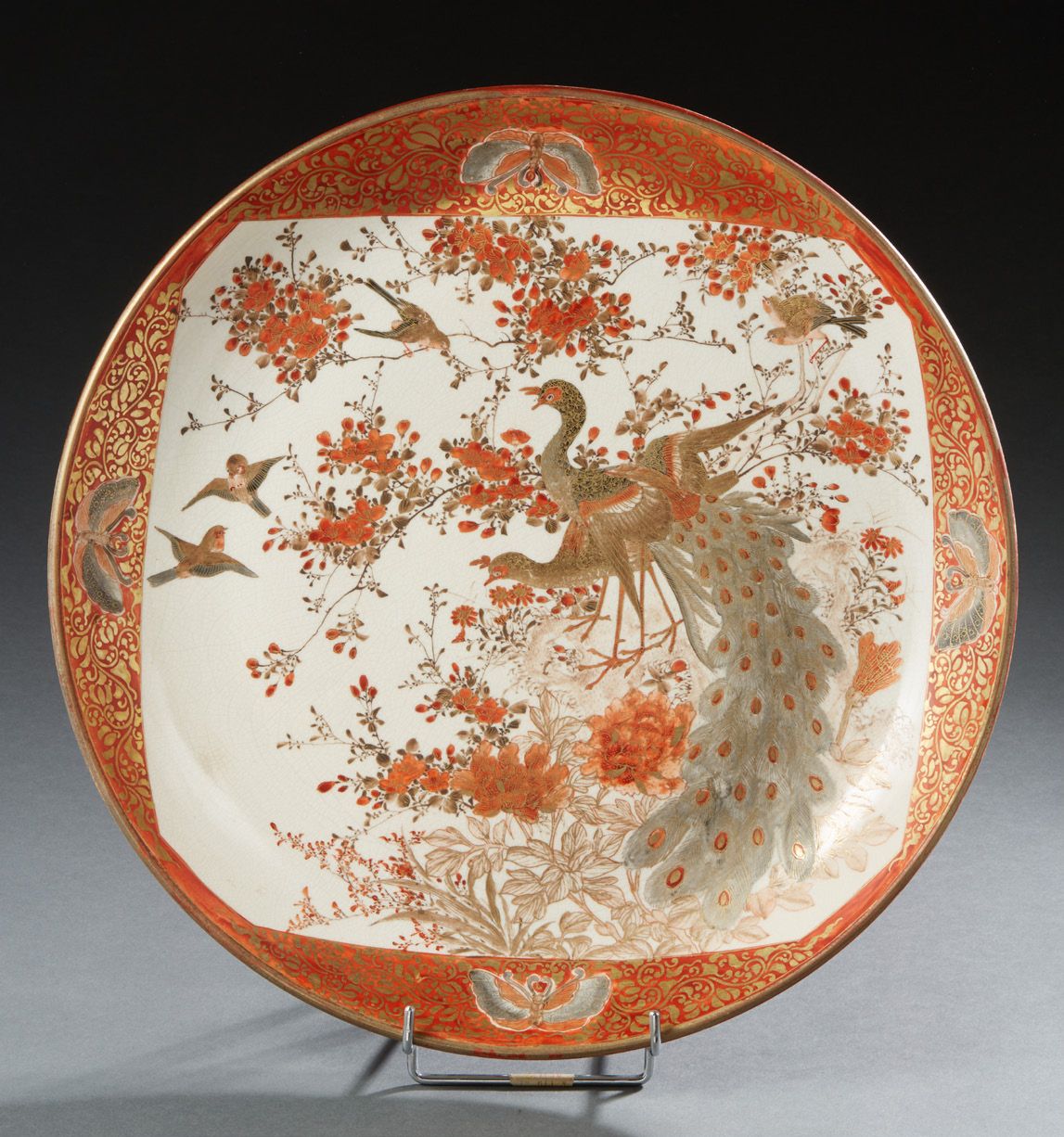 CHINE 
日本, SATSUMA

珊瑚红和金色的大型陶瓷盘，以珊瑚为背景，表现孔雀和燕子在盛开的梅花旁的蝴蝶框架中的自然主义图案。

19世纪

直径：3&hellip;