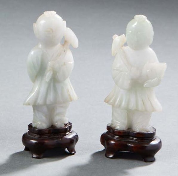 CHINE Two light jade figurines representing standing hoho twins holding an axe. &hellip;