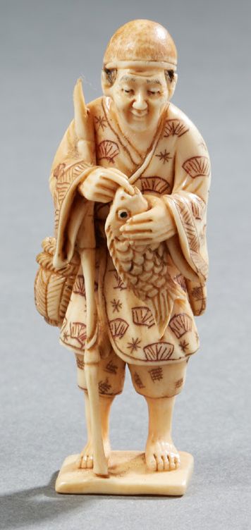 JAPON Netsuke en ivoire sculpté représentant un pêcheur debout tenant une carpe &hellip;