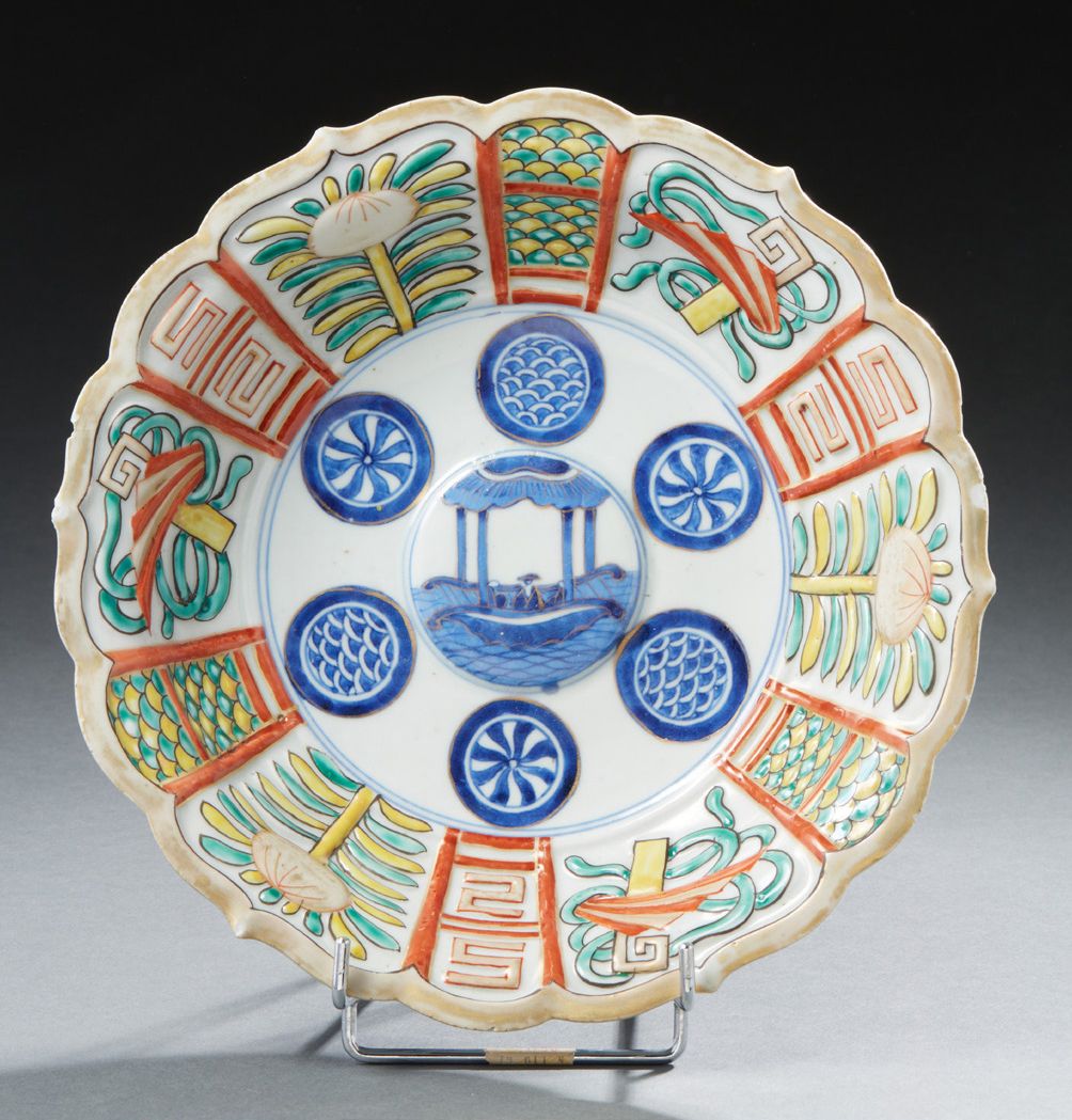 JAPON 一个圆形的瓷碗，边缘有轮廓，用蓝色釉下彩装饰，中央有一个小船，周围有六个门，用多色和金色装饰的水果和贵重物品，是卡拉克风格。背面有四个字的标记 19&hellip;