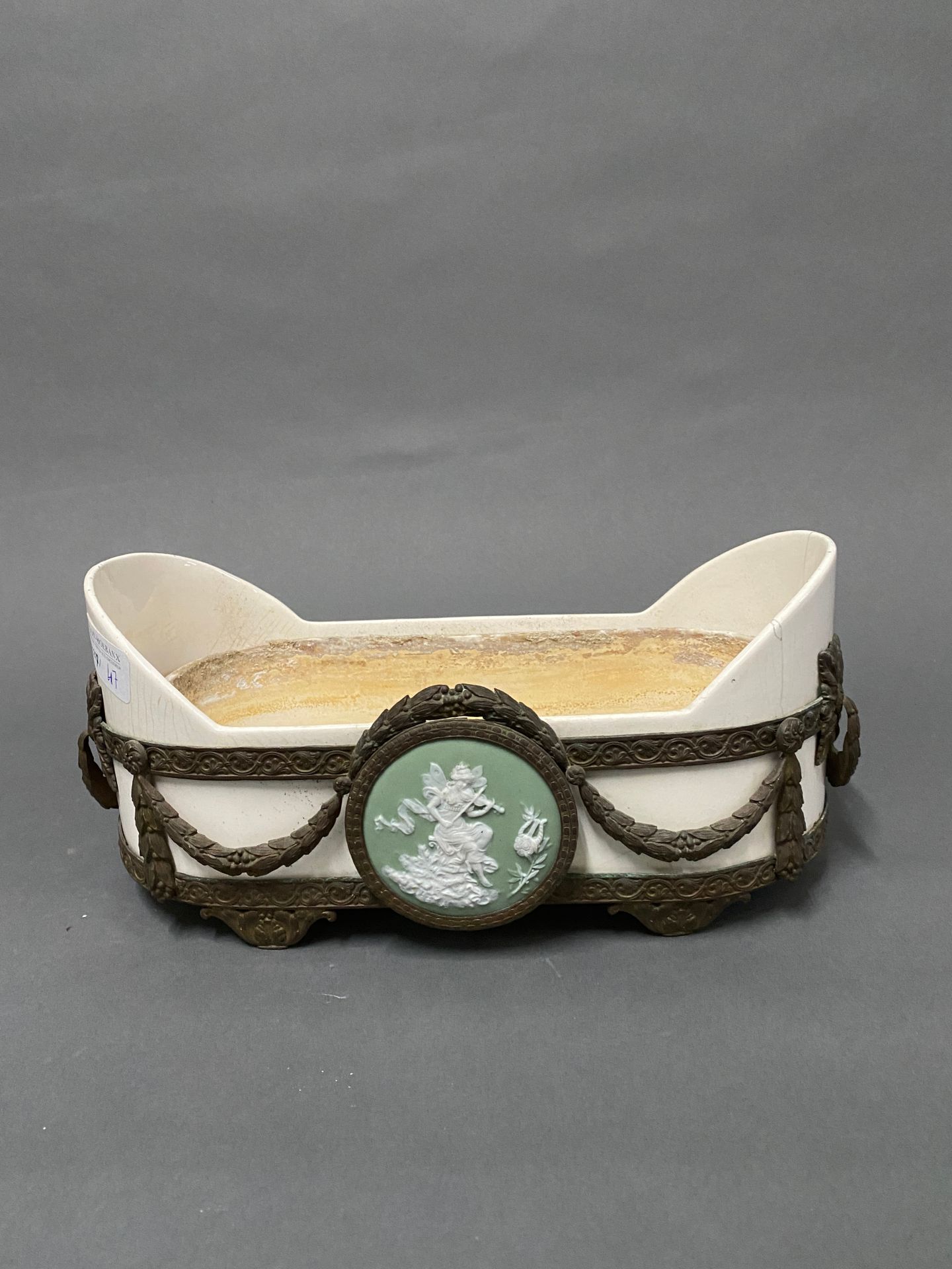 Null 维也纳

椭圆形的小陶瓷花盆，装在黄铜框架里，上面装饰着韦奇伍德风格的绿底白字的饼干状徽章。

高：12 - 长：28 - 宽：14厘米

(裂缝)