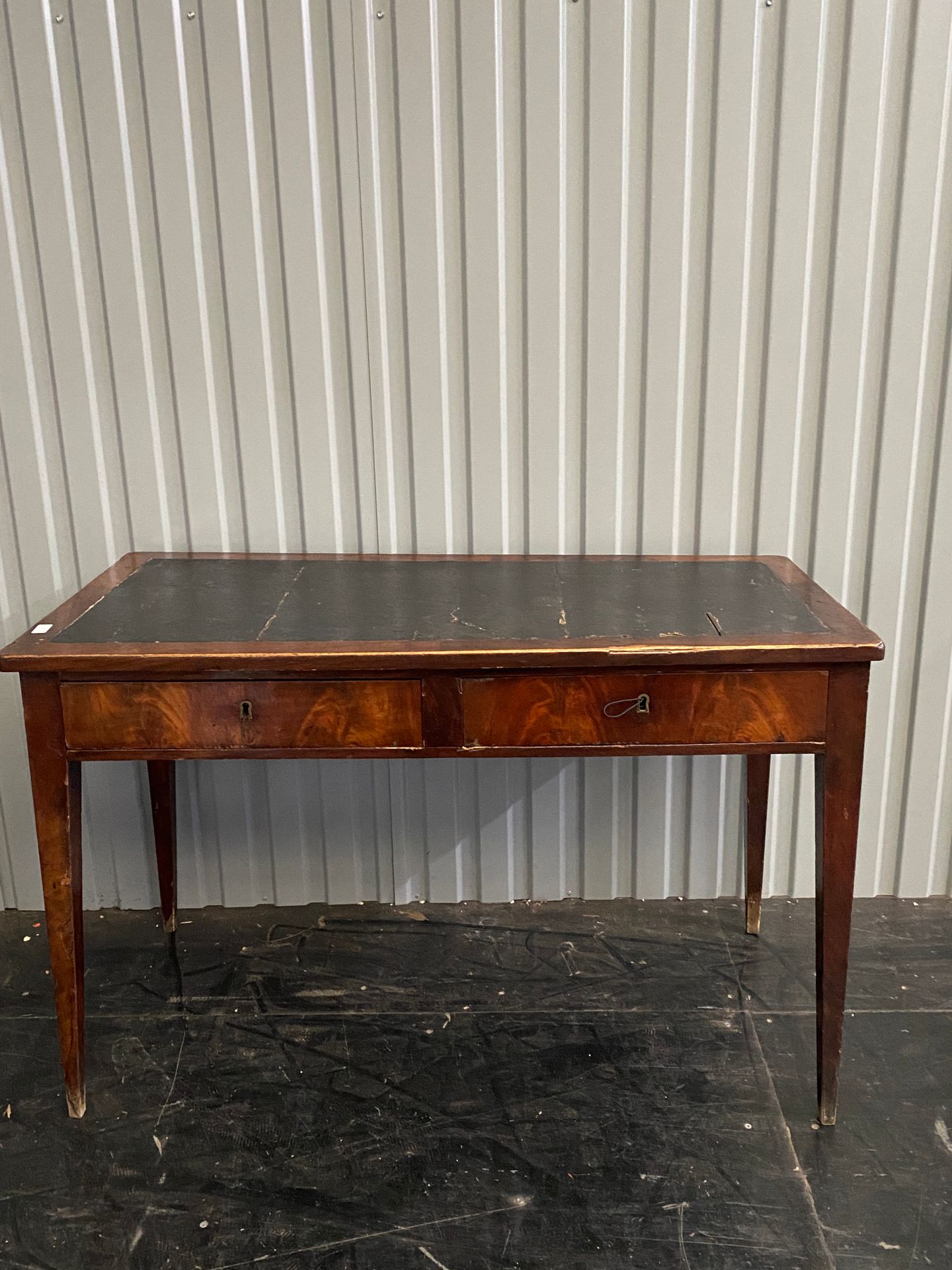 Null 桃花心木和桃花心木饰面的平面书桌，它前面有两个抽屉，皮革桌面，锥形腿。

19世纪初

单板开裂

高：73 - 长：113 - 宽：56厘米