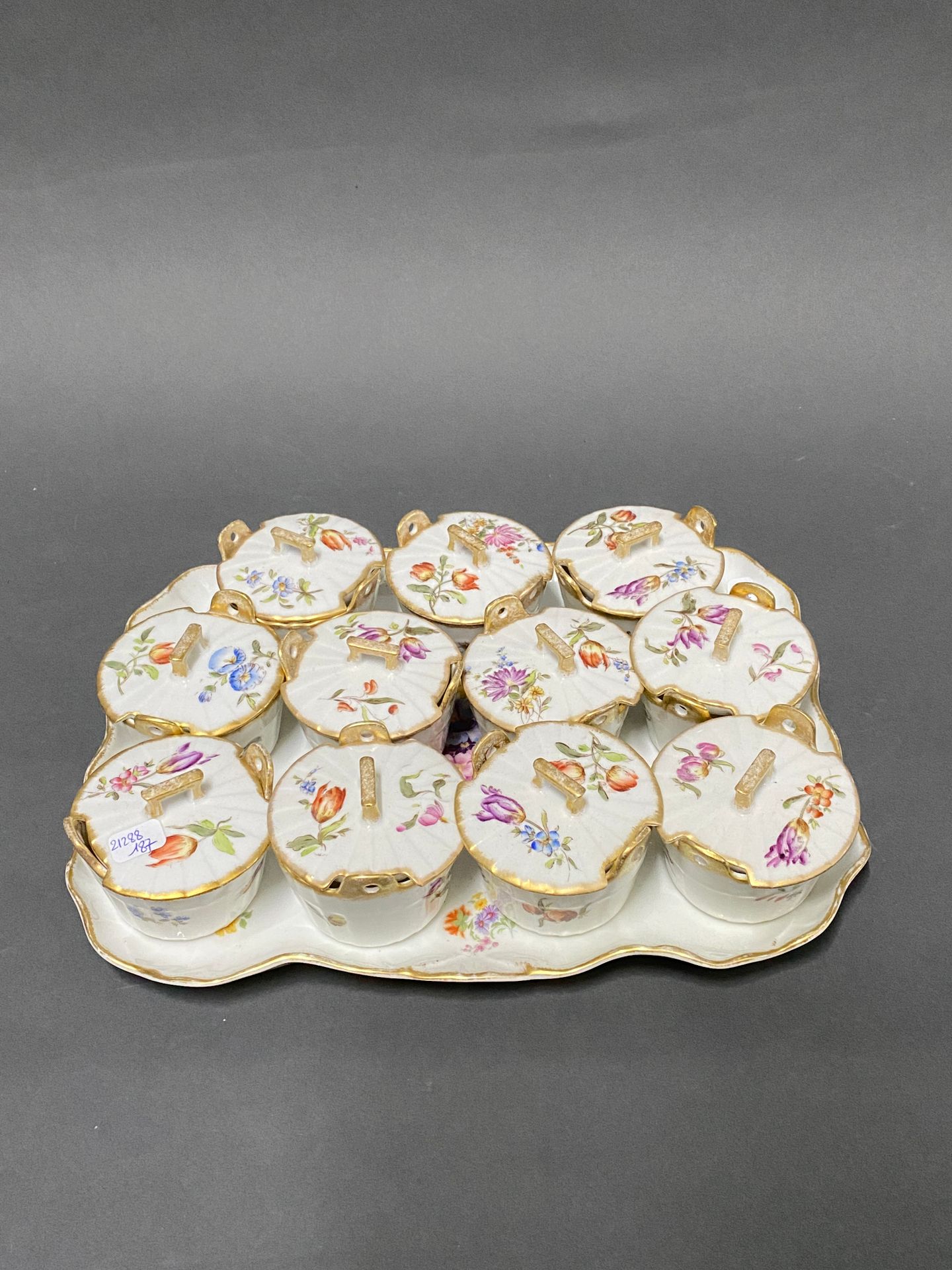Null 一套11个有盖黄油盘和一个带花饰的瓷质托盘

20世纪初

29 x 33厘米（托盘）