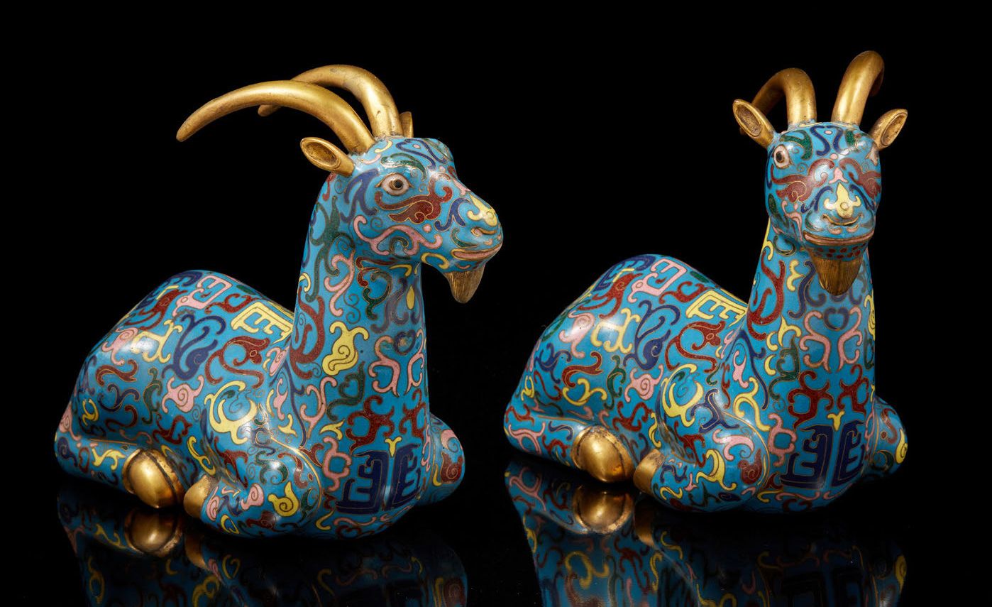CHINE, XXe siècle 一对躺着的山羊，蓝底鎏金铜和多色掐丝珐琅，装饰着古朴和风格化的图案。
尺寸25 x 19厘米