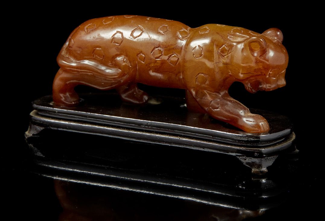 CHINE, XXe siècle 焦糖棕色的石头动物主题，代表一只咆哮的豹子。
在一个木质底座上。
长度：9.5米