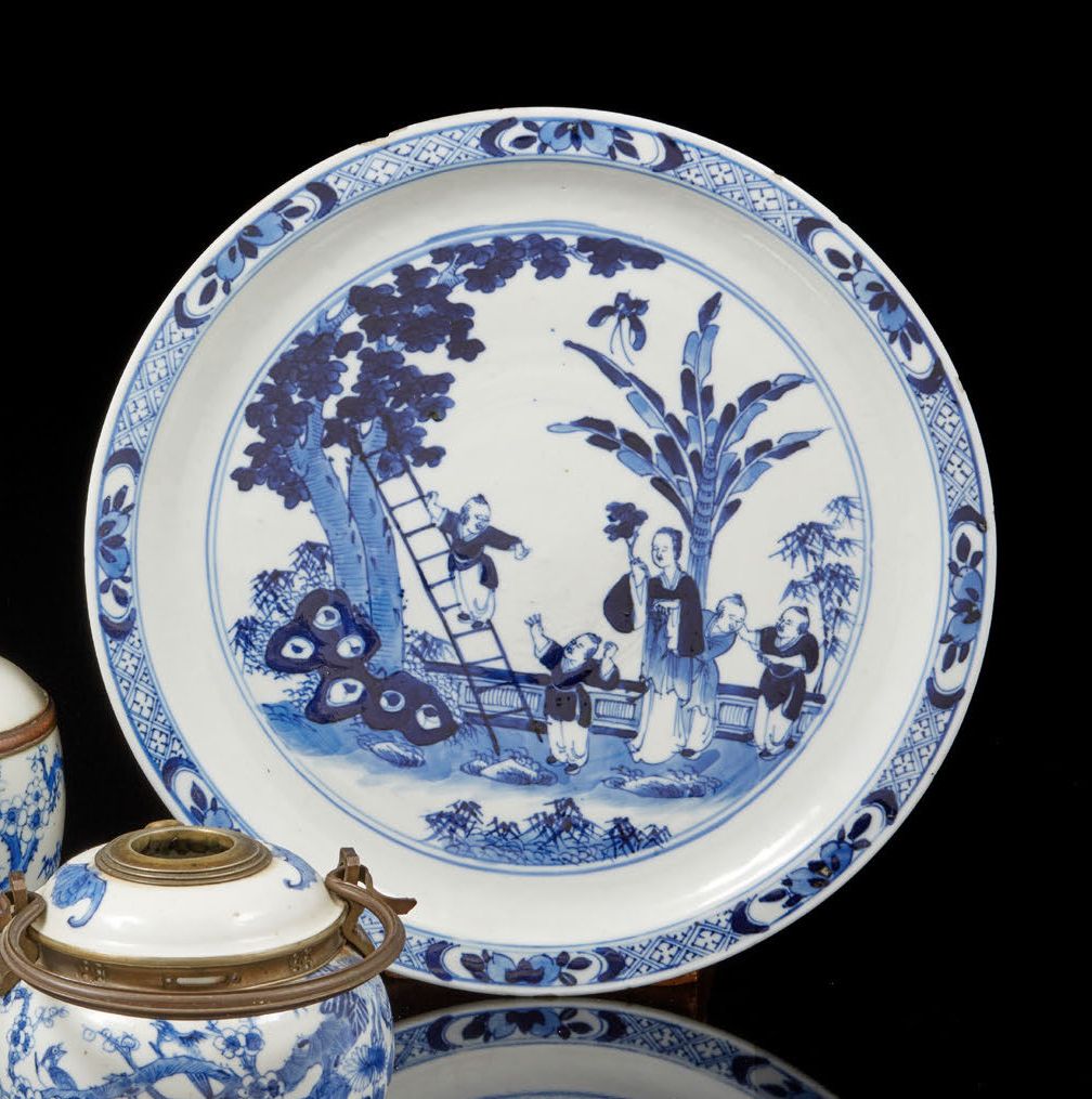 CHINE, XIXe siècle 一个青花瓷盘，上面装饰着一个年轻女人和孩子在花园里采摘。背面有 "宣德 "字样的伪文。
D. 26,5厘米（有缺口和划痕）&hellip;
