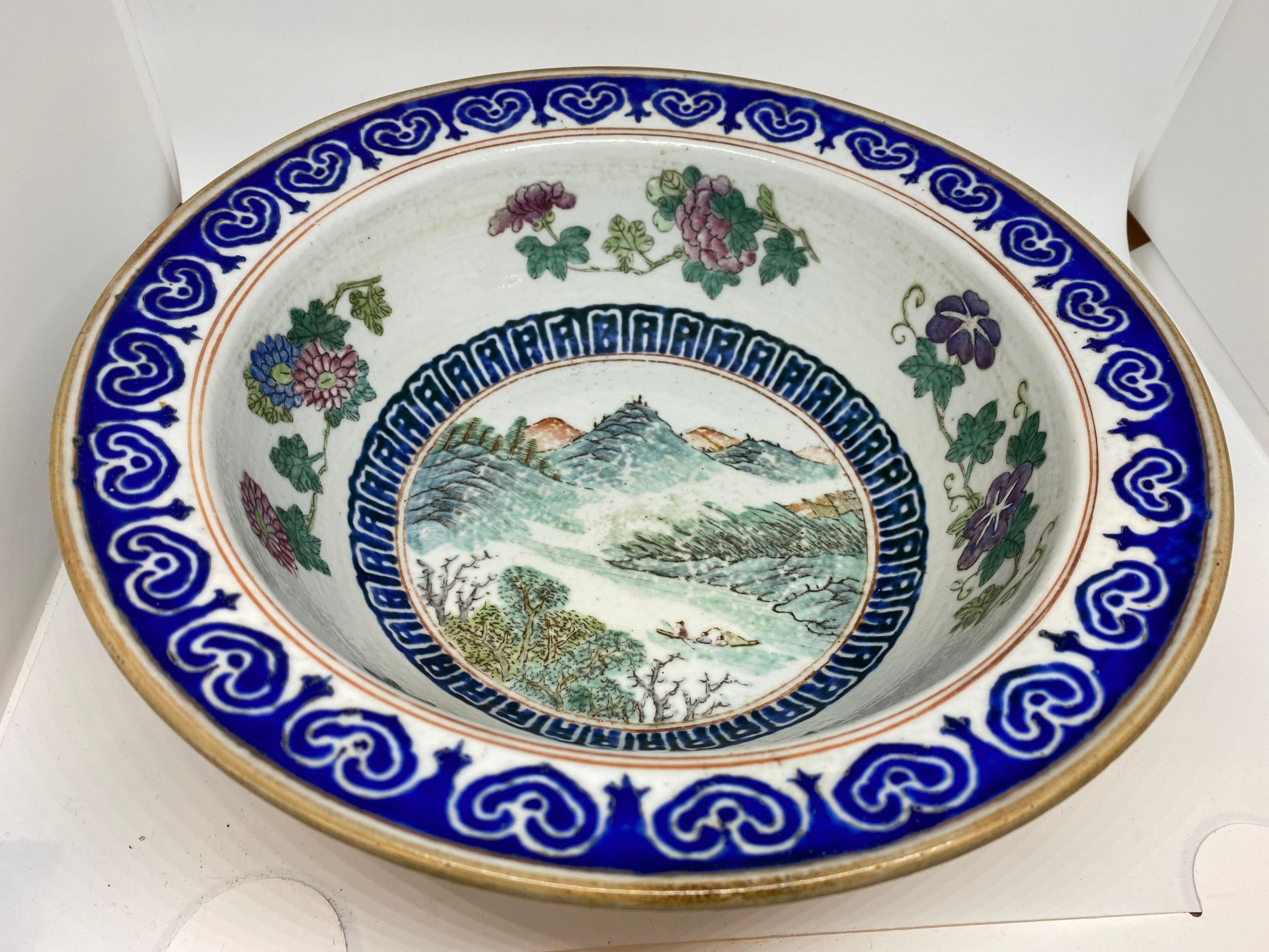 Null 中国
圆形瓷碗，装饰有山水和花卉。背面是棕榈树。
D : 28厘米。
(芯片)