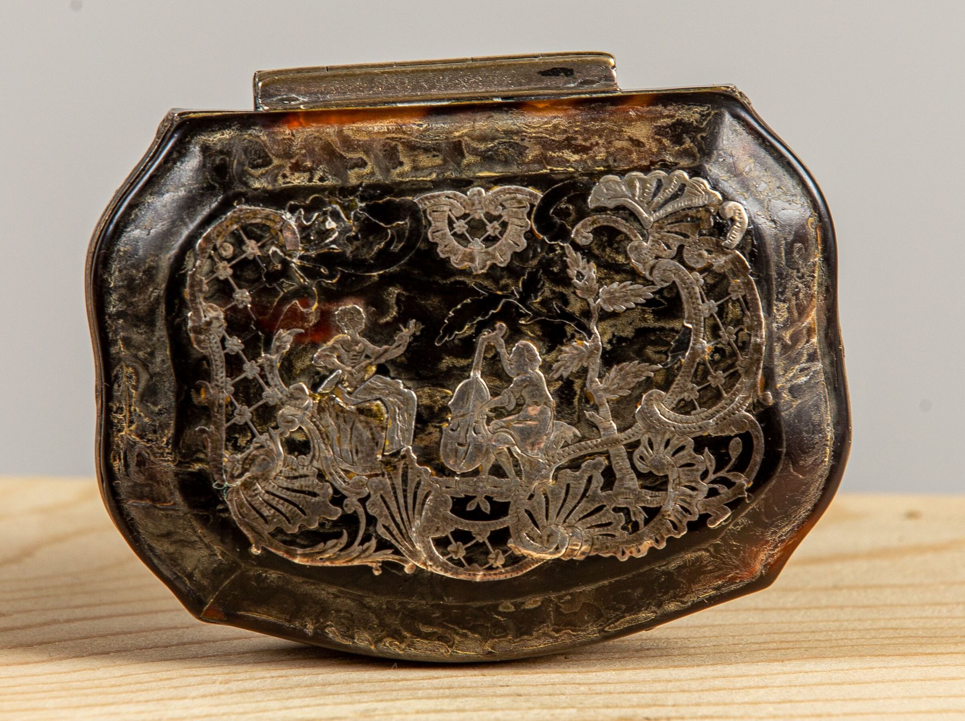 Null 龟壳鼻烟盒，盖子上有两个音乐家的装饰，在一个罗盖尔和刺桐叶的框架里。 
那不勒斯或巴黎，18世纪piqué工作。 
高_3厘米，宽_8厘米，长_6,5&hellip;