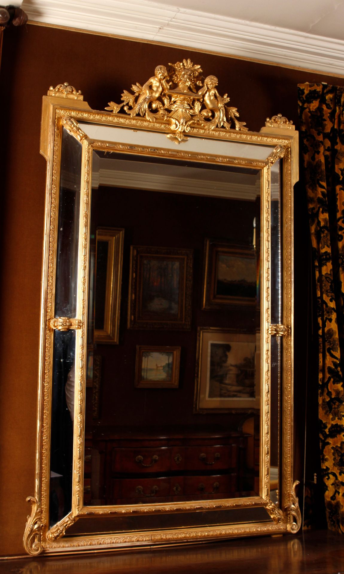 Grand Miroir à pare-closes en bois stuqué et doré, fronton orné d’amours, frise &hellip;