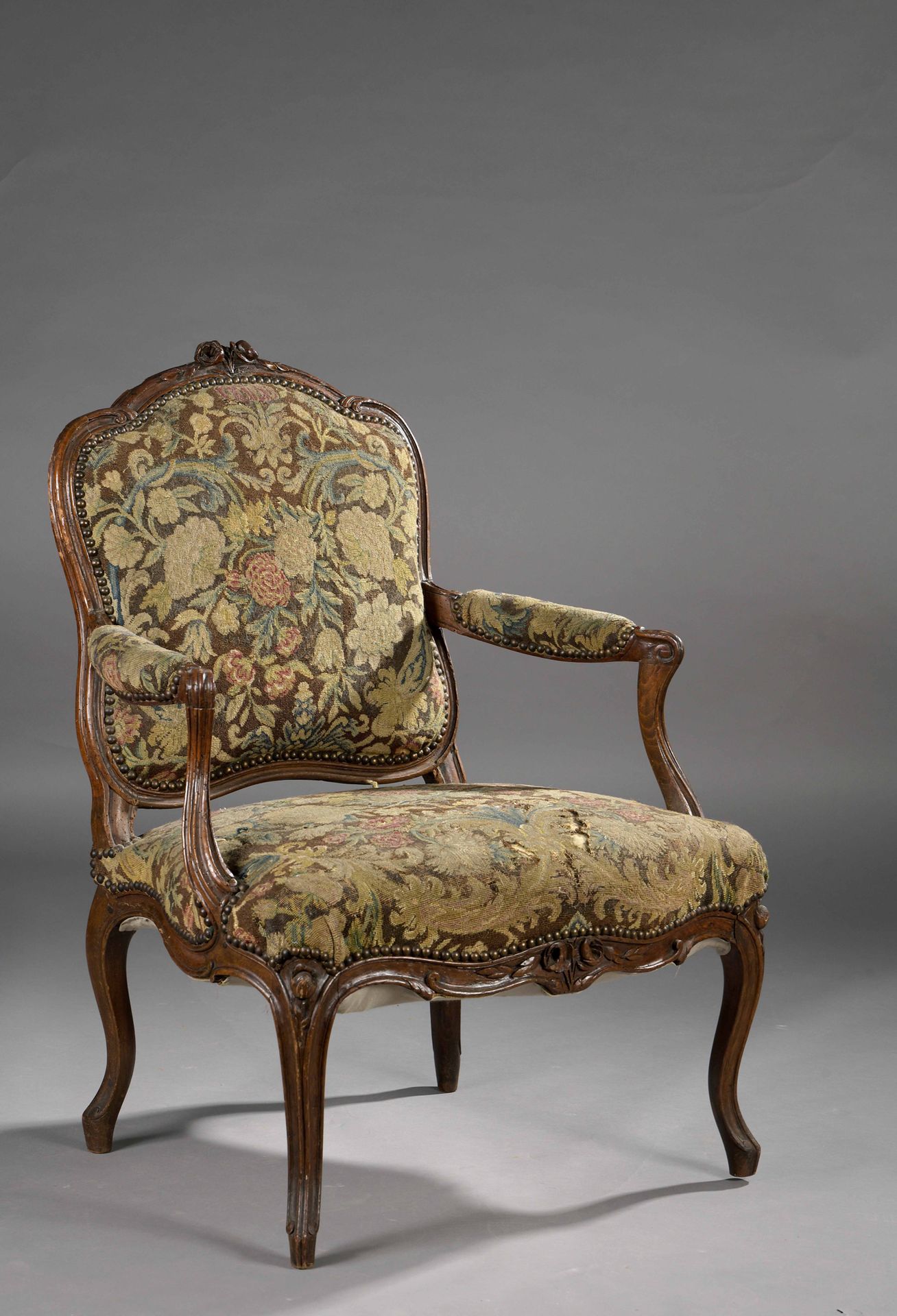 Null 一把成型的、雕刻的和着色的胡桃木扶手椅，有一个平坦的多叶背，装饰着花和叶子，靠在拱形的腿上，上面覆盖着挂毯。

(皮带未检查，事故和缺失的部件)。

&hellip;