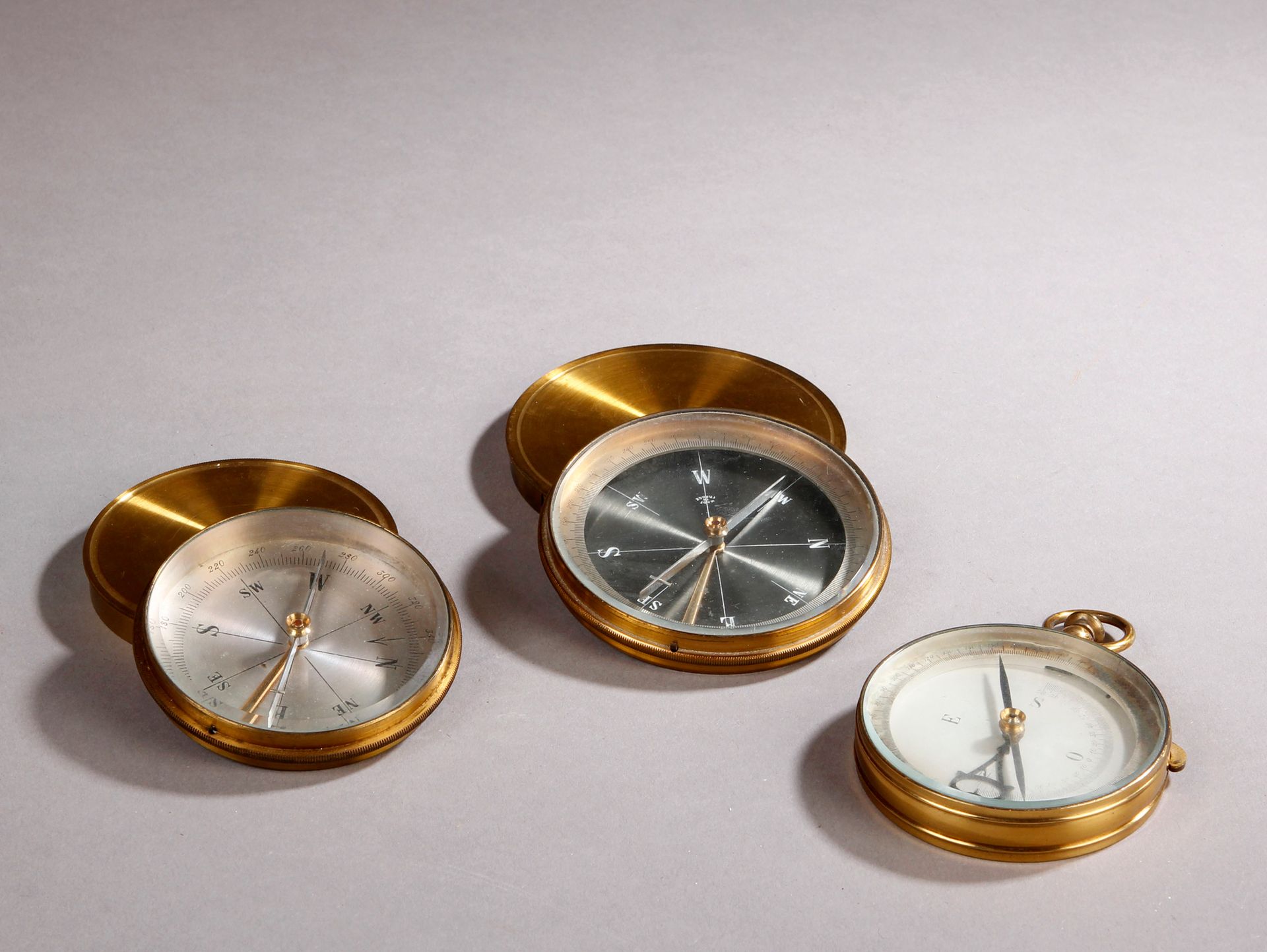 Null Three brass compasses, two with cover and one in the form of a pocket watch&hellip;