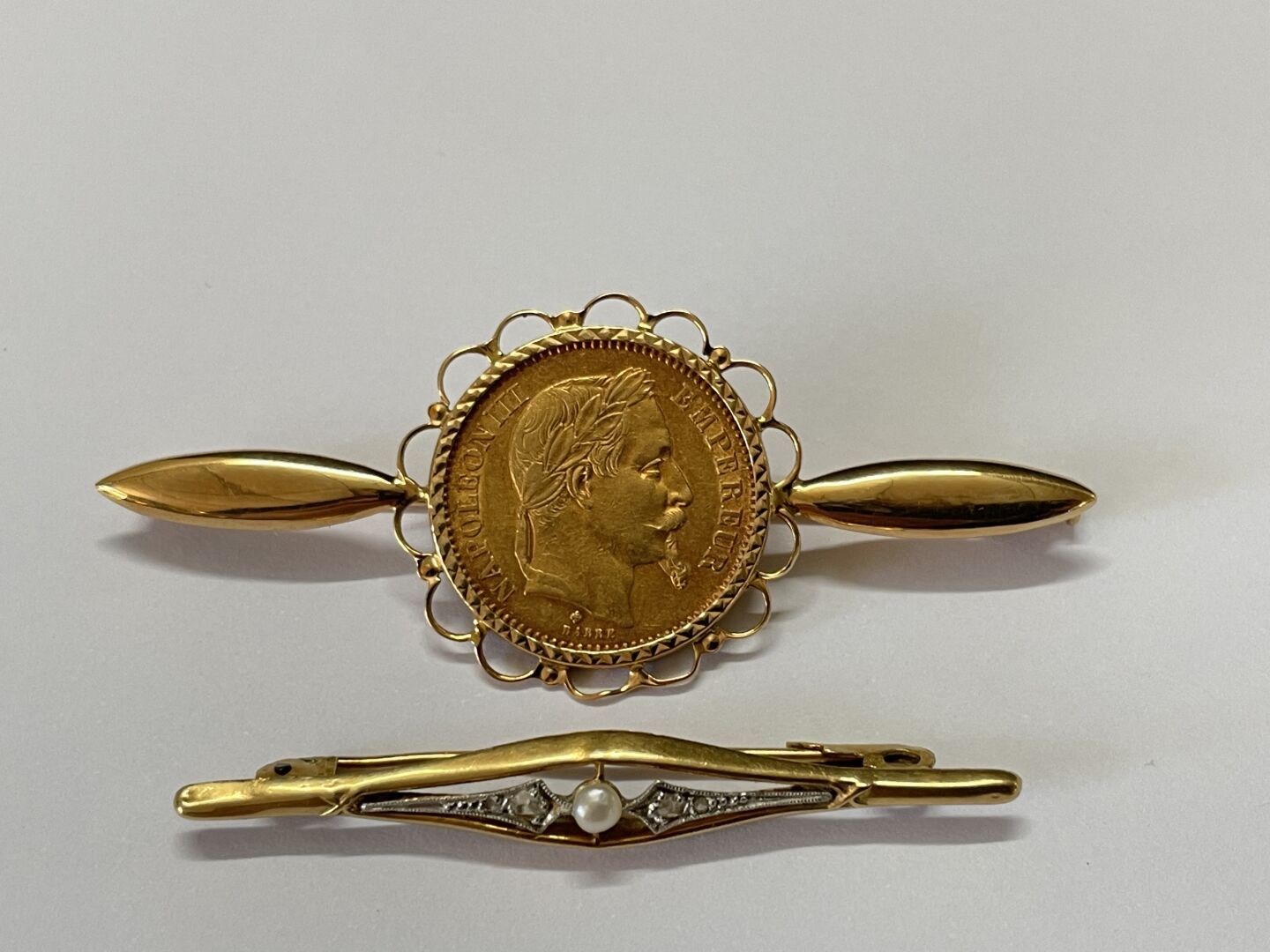 Null 镶嵌有1864年拿破仑三世20法郎金币的黄金胸针。

长：6.5厘米。

附有一枚750°/00的黄金胸针，上面有一颗小珍珠。

总重量：13.96克
