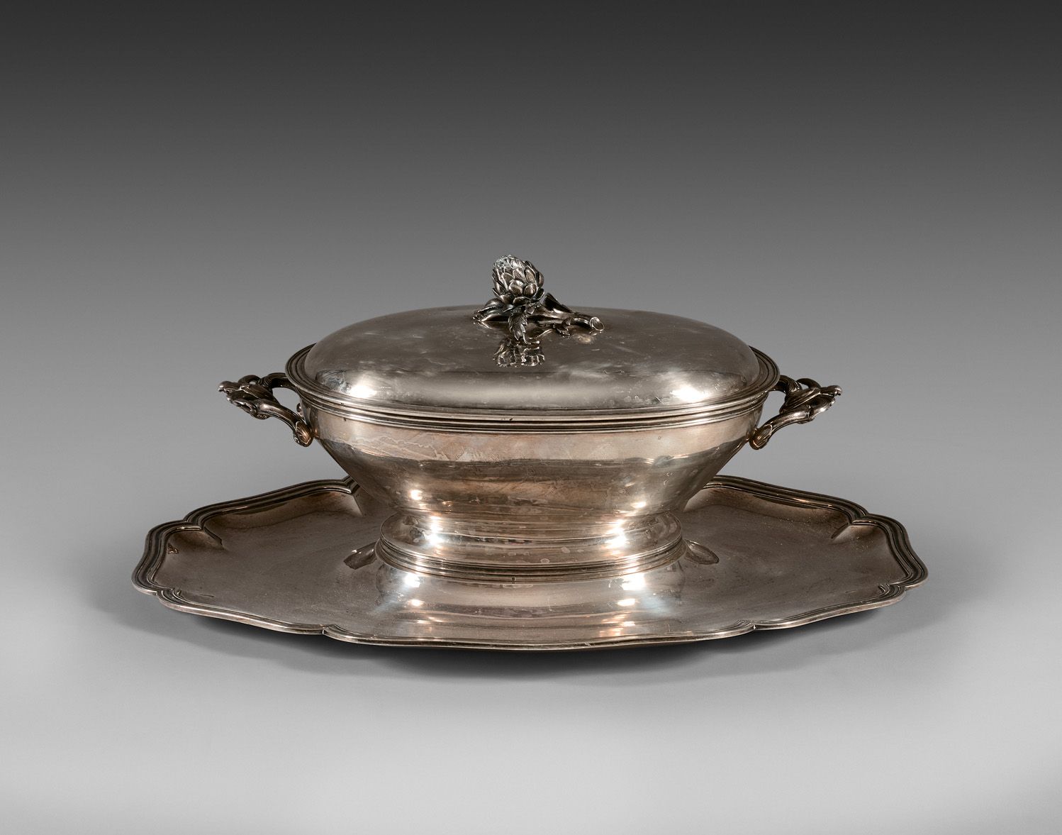 Null A silver oval soup tureen with two leafy handles and an artichoke handle. I&hellip;