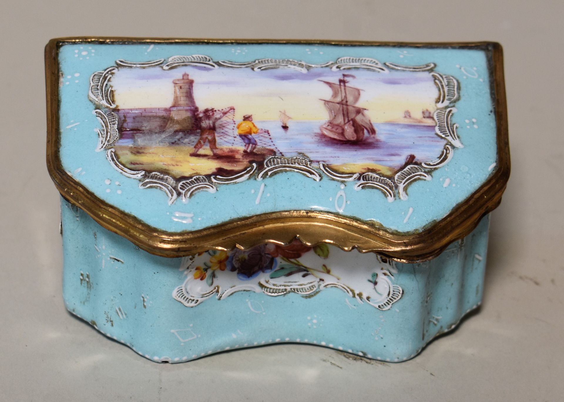 Null 一个蓝色珐琅质的旅行者写字盒，盖子上有一个海港场景。有两个墨水瓶。英国，巴特西，18世纪末。高度4.5 - 宽度10 - 深度6厘米

(铜质安装松动&hellip;