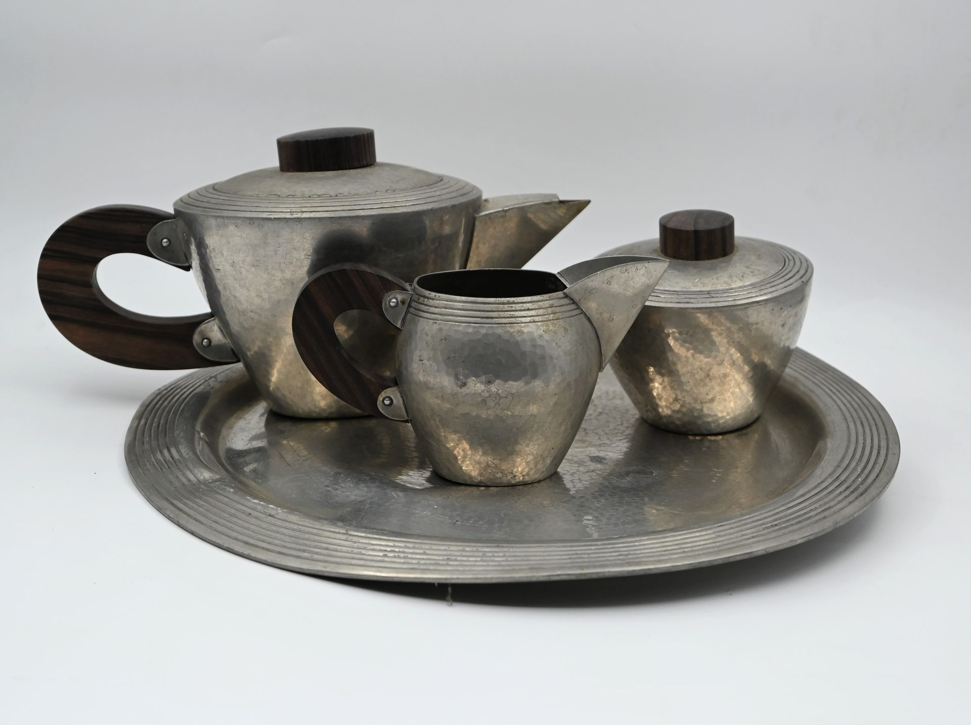 Null René DELAVAN（活跃于1926年至1958年）。一个锤击的锡镴咖啡服务，包括一个咖啡壶，一个牛奶壶，一个糖碗和一个圆形托盘，有模制的边缘，紫&hellip;