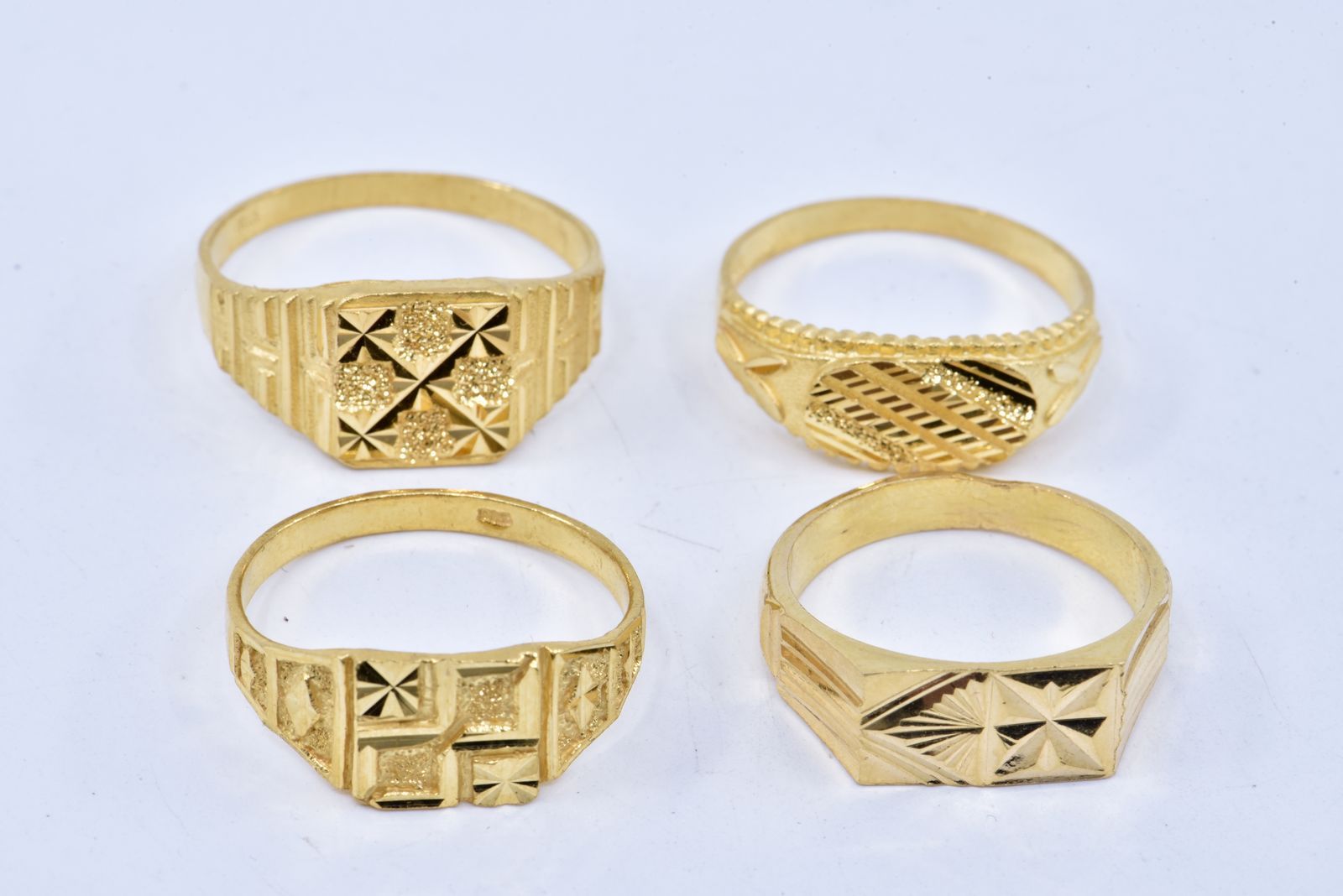 一系列四枚戒指或徽章，刻有风格化的图案。22K黄金，916/°°°°重量 