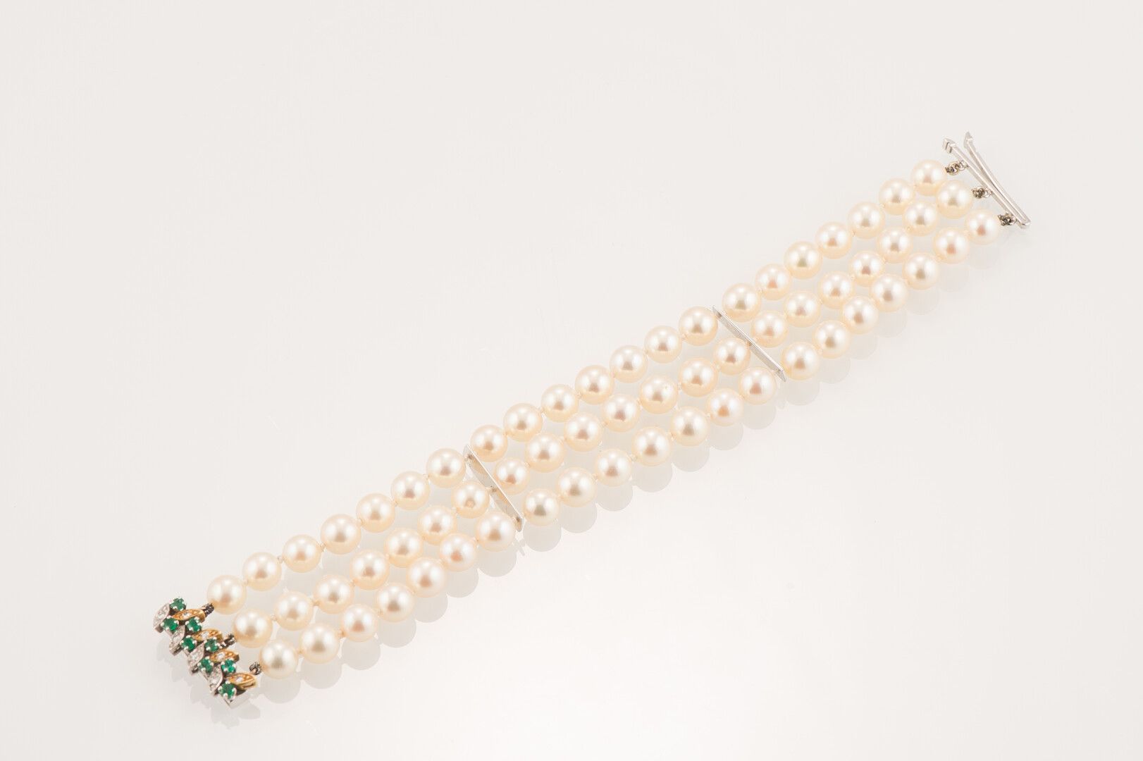 Null 手镯装饰有三排养殖珍珠，共63颗珍珠（直径约6.7毫米），750千分之一的白金扣饰有8颗绿宝石和8颗钻石（总重量：42克）（长度：17.5厘米