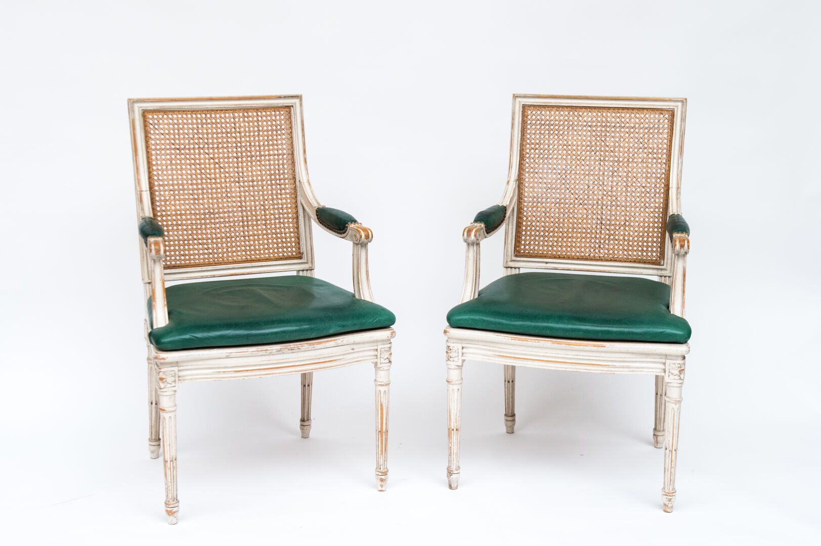 Null 一对白色漆木扶手椅，女王风格的靠背，凹槽腿，靠背和座椅都有绿色皮垫。路易十六风格（高：96厘米，宽：56厘米）