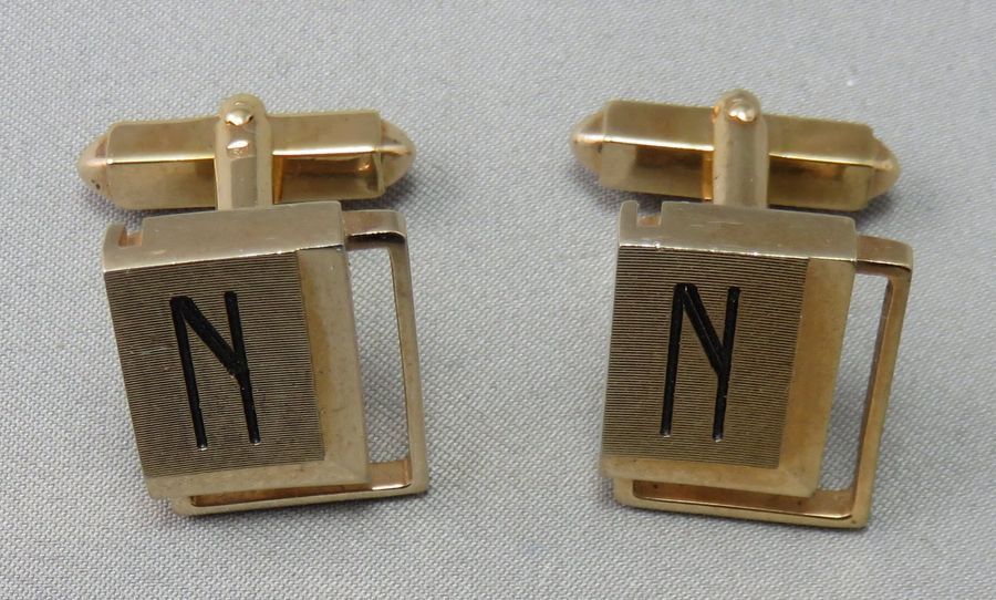 Null BOUTONS DE MANCHETTE en métal doré, rectangulaires et ajourés, monogrammés.