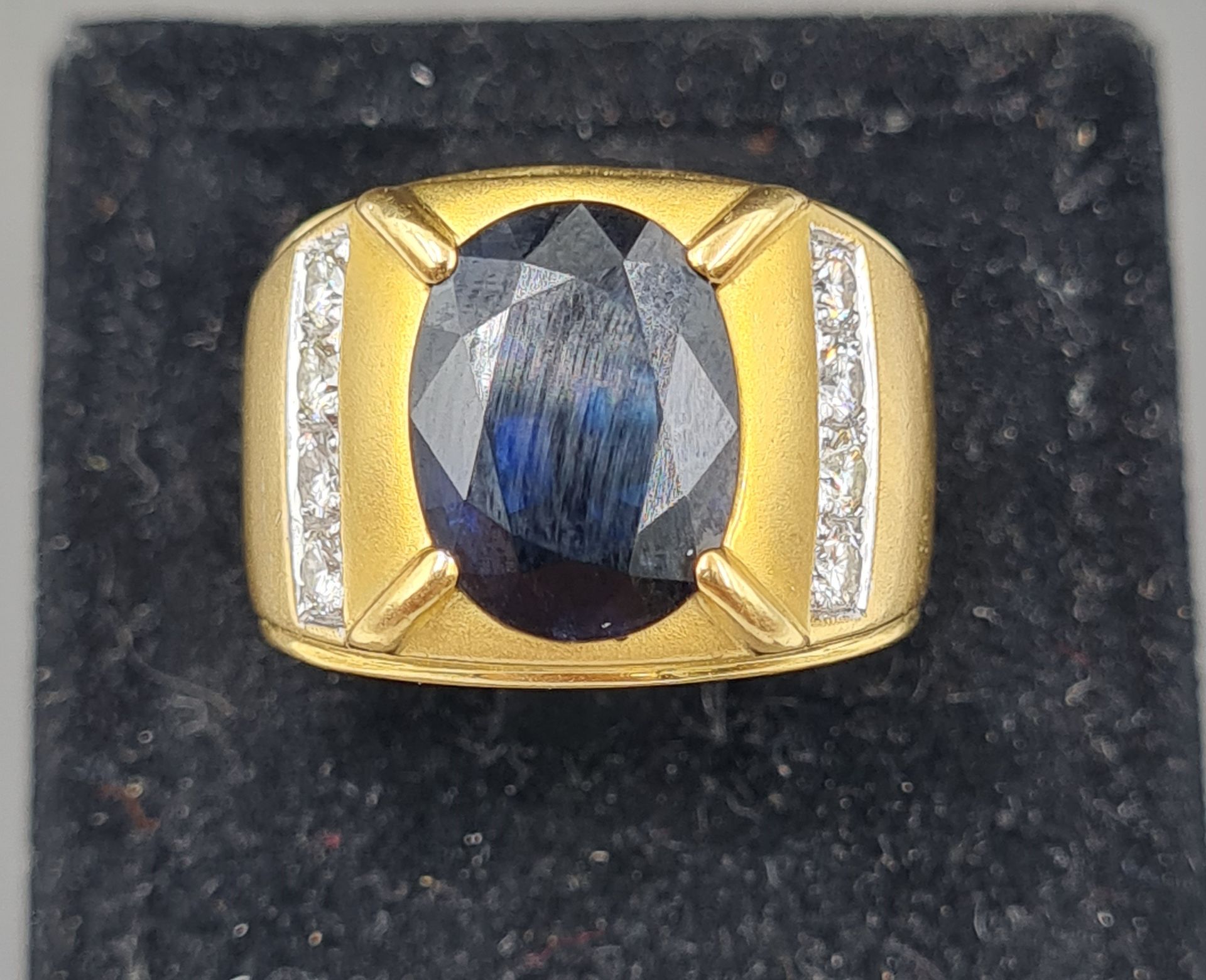 Null 750°的18K黄金戒指，镶有一颗重约4克拉的椭圆形蓝宝石和两行4颗明亮式切割钻石。TDD: 60, 毛重: 19.07 g (须经检查)