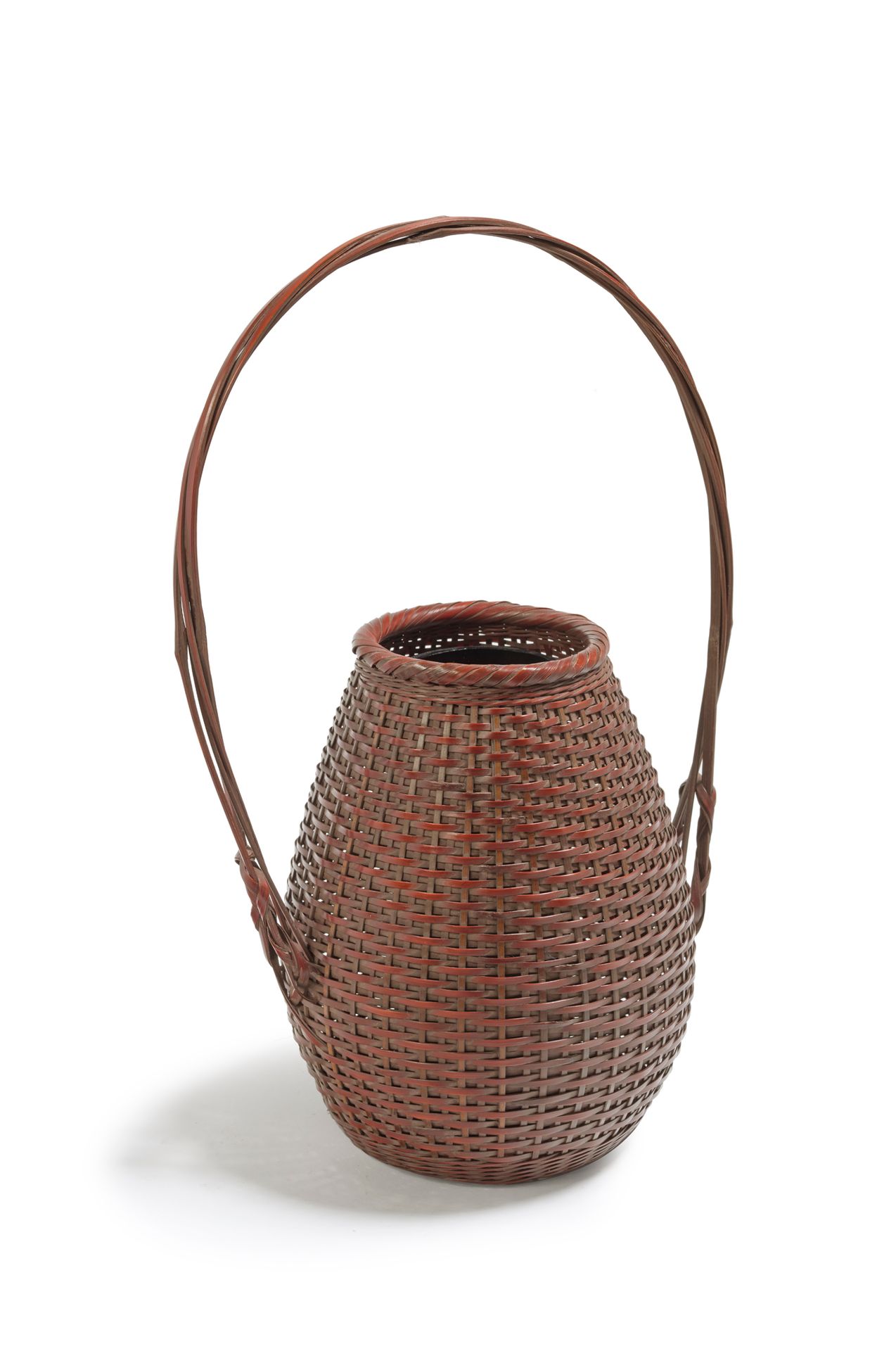 JAPON - XXe siècle 红棕色的竹制花篮，呈卵形，有规则的横向编织，颈部以斜向编织结束，手柄由四股绞合而成。
，签名为Honan。
，高35厘米。