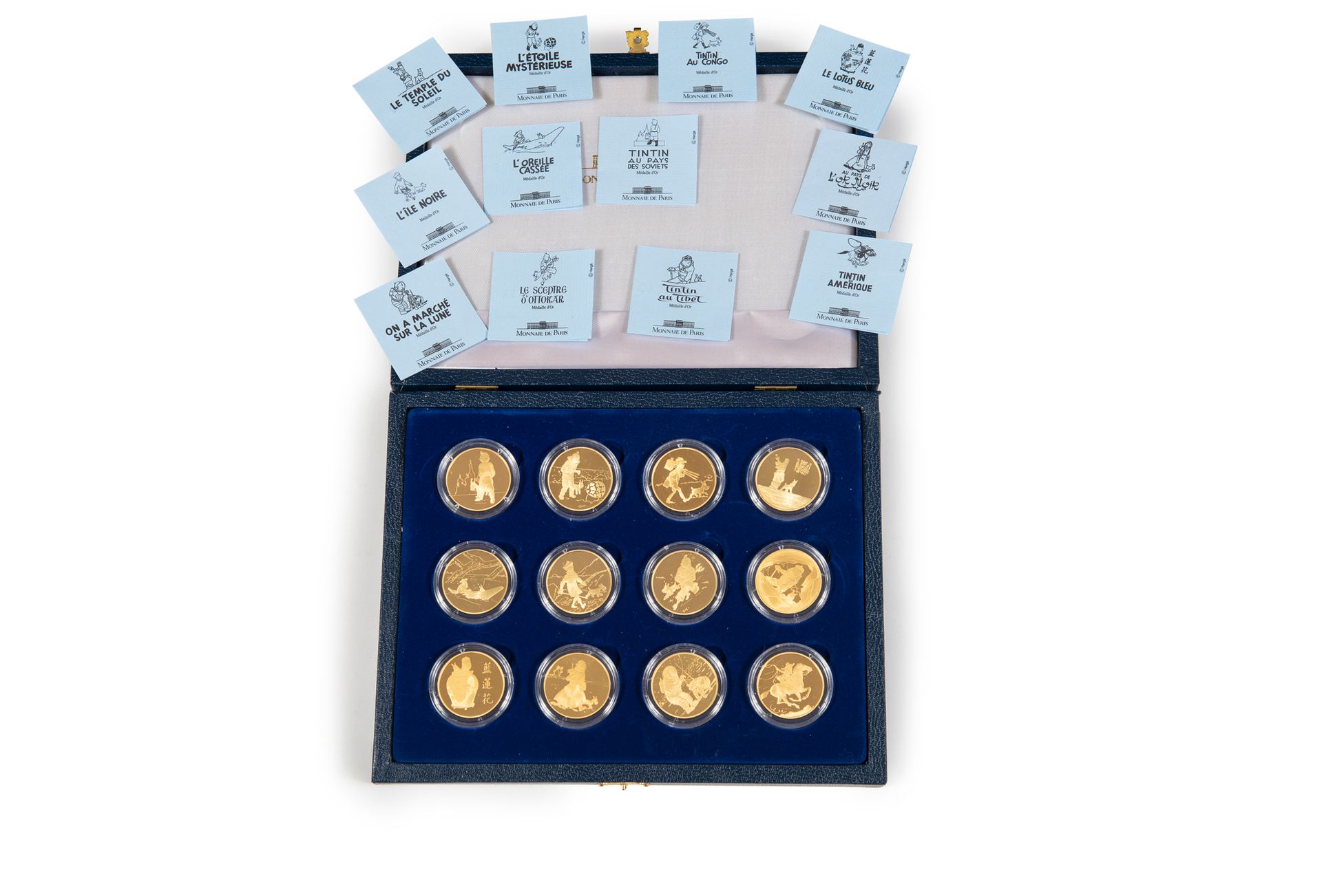 Null 丁丁 - 金币：蓝色皮革包裹的盒子，上面有代表丁丁和白雪的金色字体，包括巴黎博物馆为1993年赫热去世十周年而编辑的12枚金币（12.75克精金/枚）&hellip;