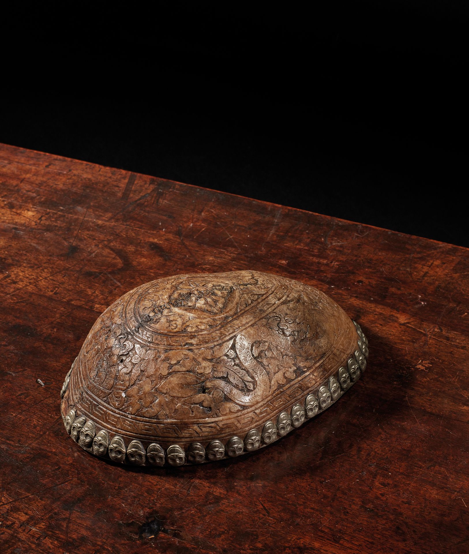 TIBET - XIXe siècle 骨质卡帕拉，有凿刻的金刚经装饰，周围有龙、佛教珠宝和叶子中的无尽结，边缘装饰有镀银骷髅的楣子（小姐）
长18厘米