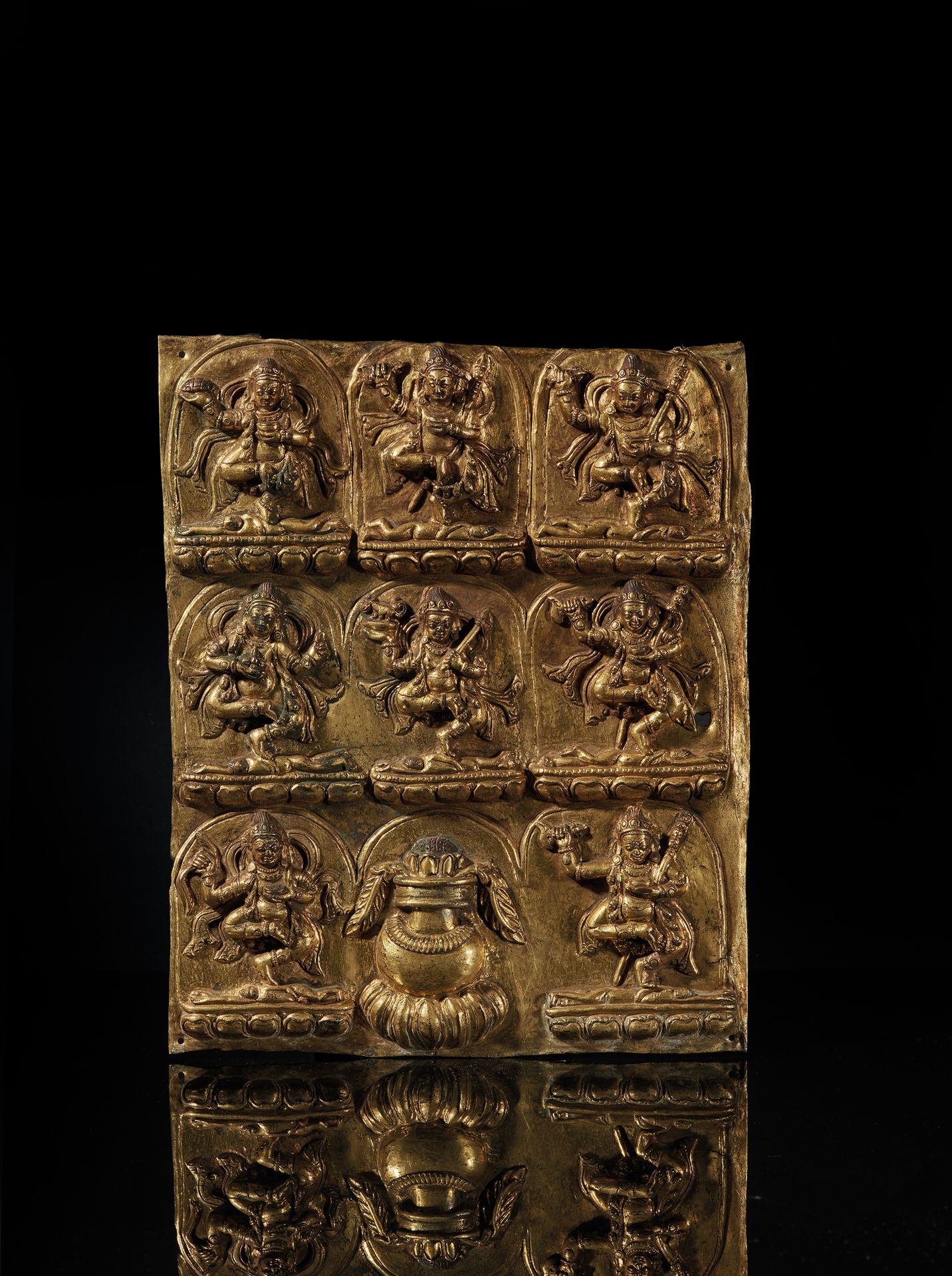 TIBET - XVIe/XVIIe siècle 一块有多色痕迹的镀金压花铜板，装饰着达摩帕拉的八个化身，他们单腿站在放在莲花形基座上的身体上跳舞，头戴腰带，&hellip;