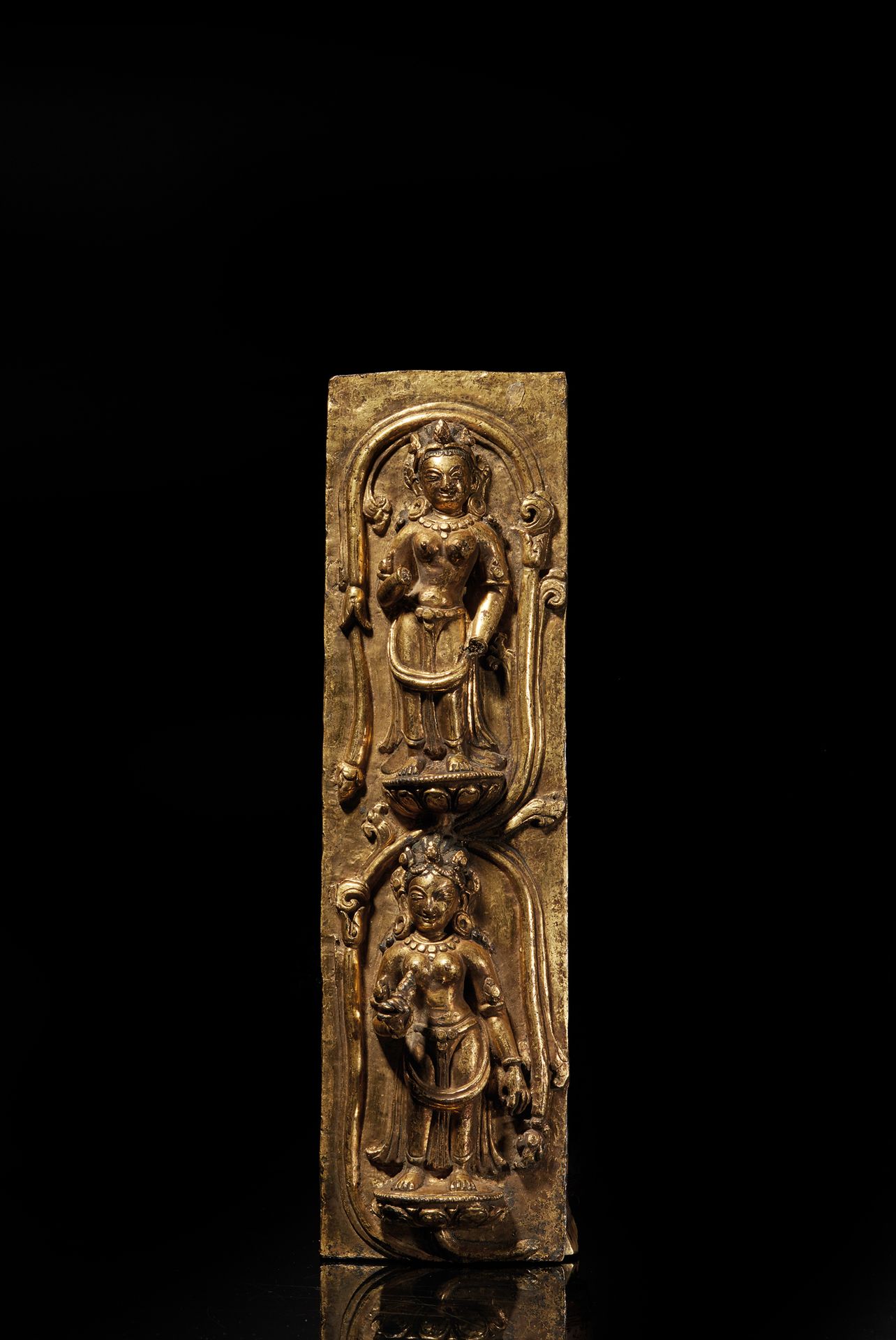TIBET, Densatil - XVIe siècle 鎏金铜牌，表现两个站在莲花上的阿普萨拉，周围是装饰有造型叶子的茎，装饰有大耳环和有造型花纹的皇冠，下&hellip;