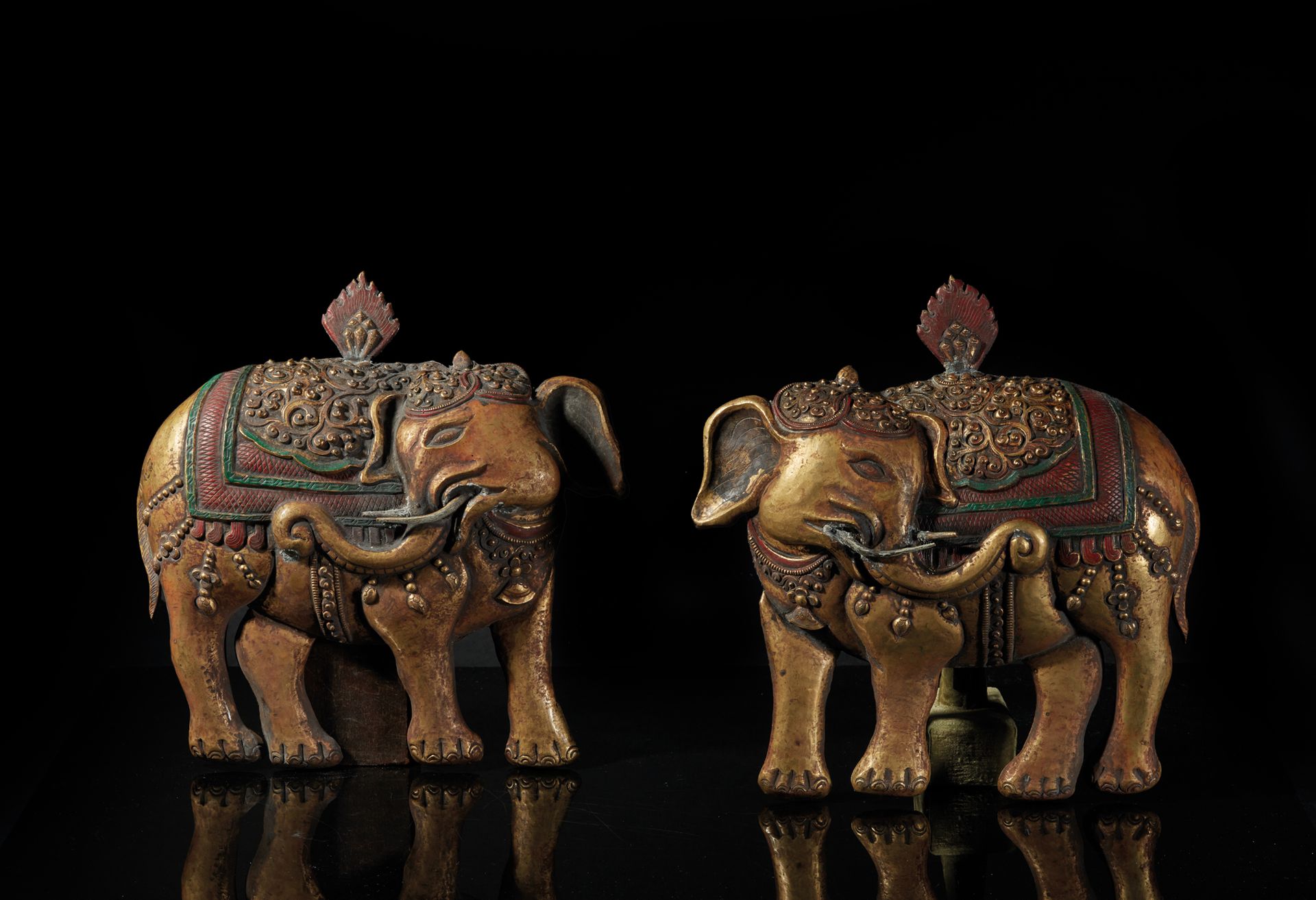TIBET - XVIIIe siècle 一对有多色痕迹的鎏金铜板，背上背着triratna，描绘了丰富的大象，它们的头向后转，花色的挂件从绿色和红色多色的鞍&hellip;