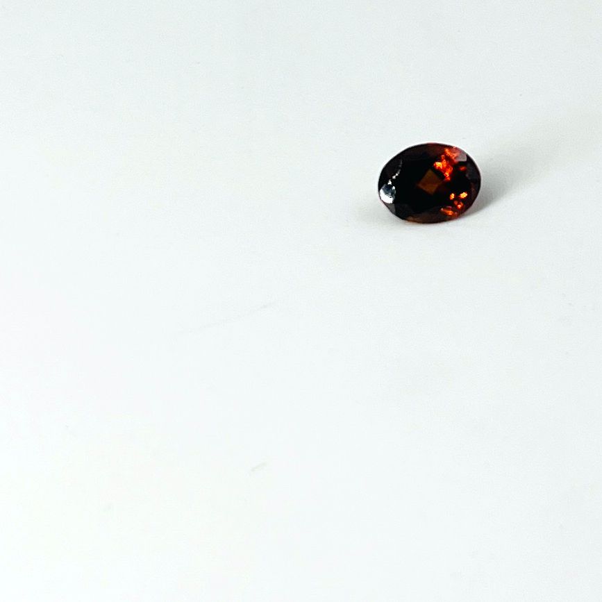 Null Oval faceted hessonite garnet weighing 2 cts.Dimensions: 0.6 by 0.8 cm