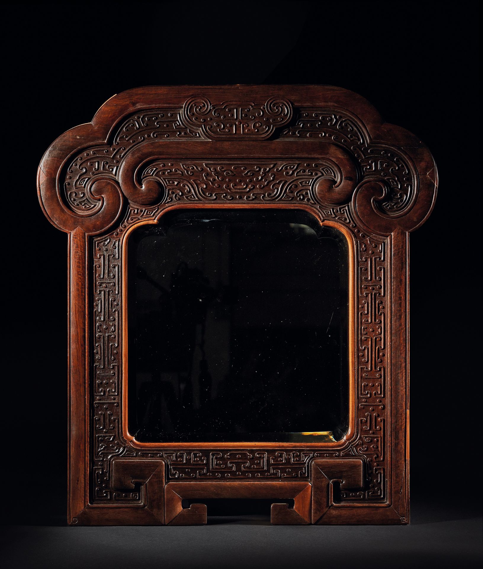 CHINE - XVIIIe/XIXe siècle 黄花梨和红木框架的镜子，雕刻着希腊的门楣和饕餮面具，上部是如意头的形状。
尺寸为66.5 x 61厘米。