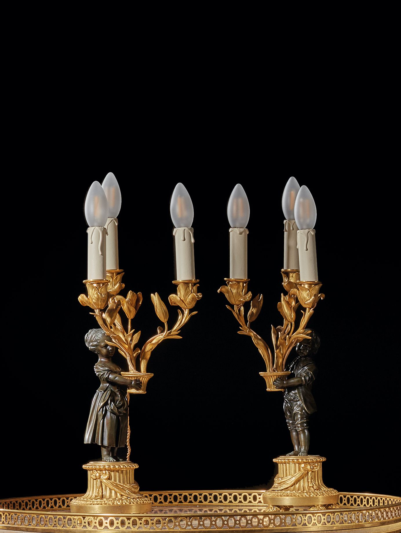 Null 一对三枝烛台，饰有一对手持花篮的儿童，青铜材质，有两种锈蚀。
路易十六风格
H.38 厘米