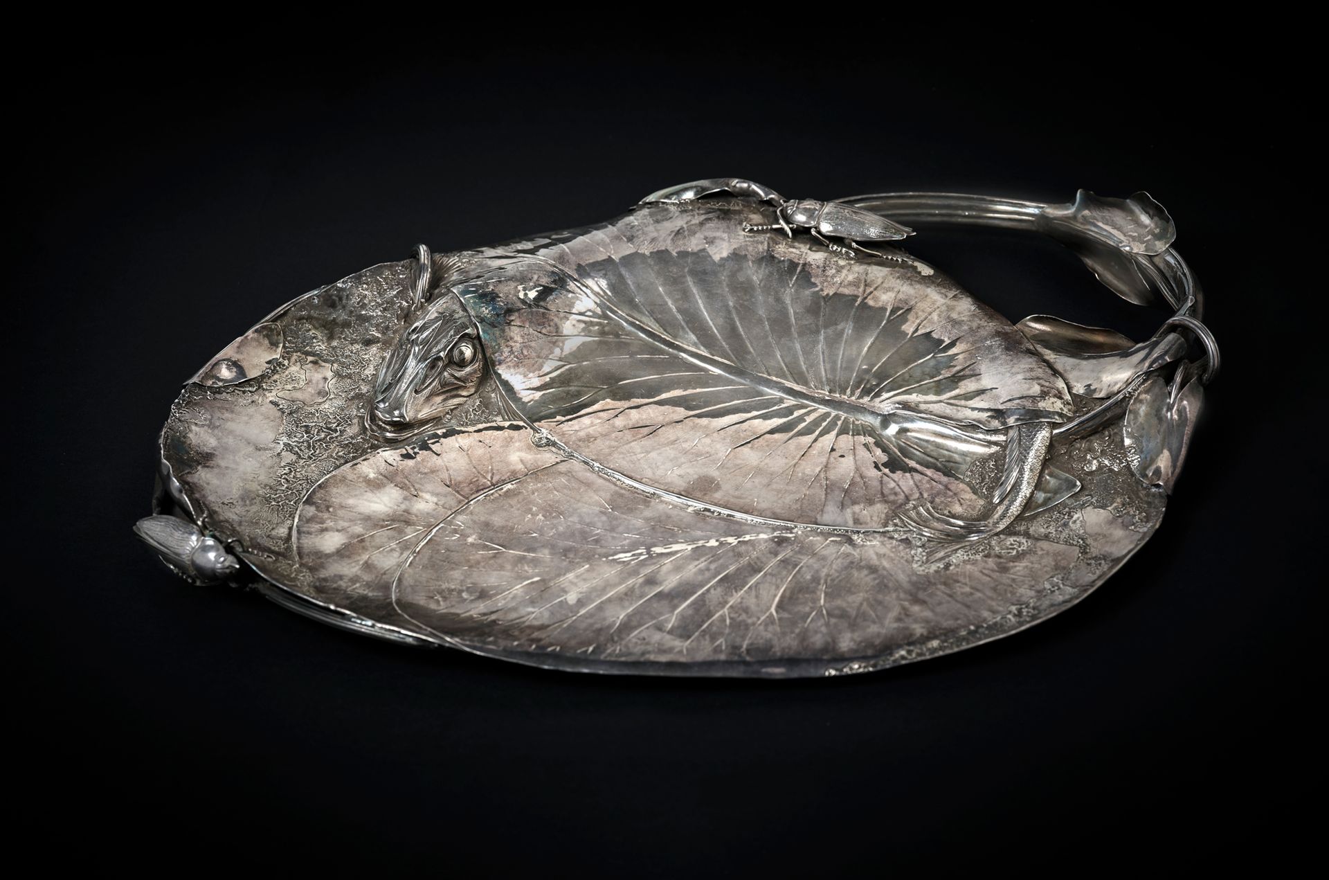 Henri HUSSON (1852-1914) 古纳尔碗，约 1906 年
银碗上装饰着一只鳕鱼，鳕鱼的身体消失在三片睡莲叶下，铠甲般的头部像尾巴一样重新出现&hellip;