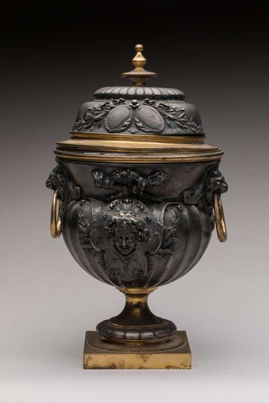 Null Oudry & Cie出版商
一个放在基座上的木制和发黑的金属瓮，上面装饰着加德隆、马斯克、卡图尔、箭筒和花环，手柄上有狮子的头像
高24厘米。