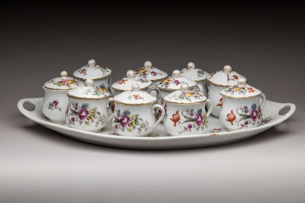 Null 11个奶油壶和它们的托盘，瓷器，有鲜花装饰、
约1900年/1930年
(一个盖子已修复)
托盘长度：43厘米