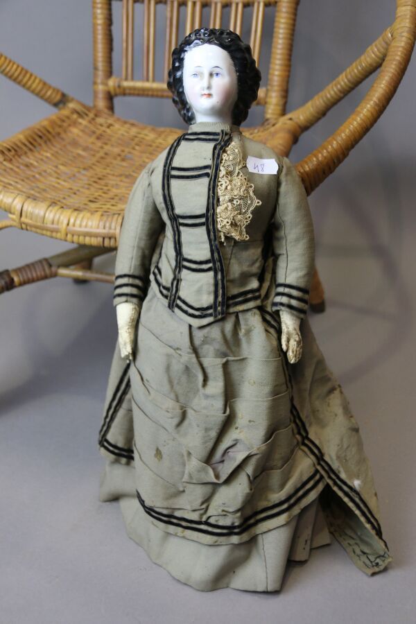 Null 德国娃娃，PARIAN型，瓷质半身头，闭着嘴，画着眼睛，黑色模压头发，直皮身体状况不佳，旧衣服，高：42厘米。