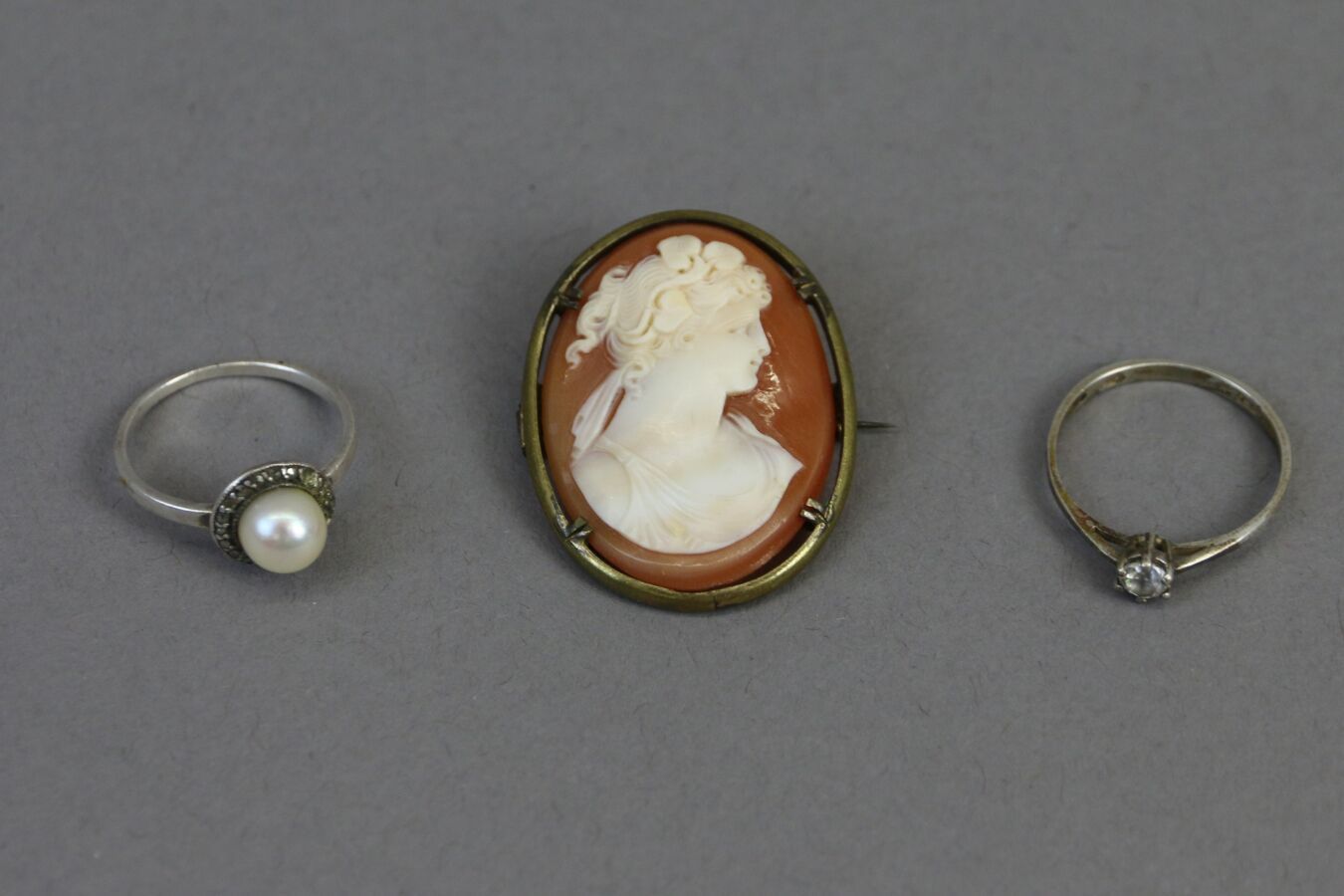 Null 
银戒指上镶嵌着一颗养殖珍珠，周围是玛瑙玫瑰。 

镶嵌有无色仿石的银质单颗戒指。

总毛重：3.1克 

一个贝壳浮雕，显示了一个女人的轮廓，是古董&hellip;