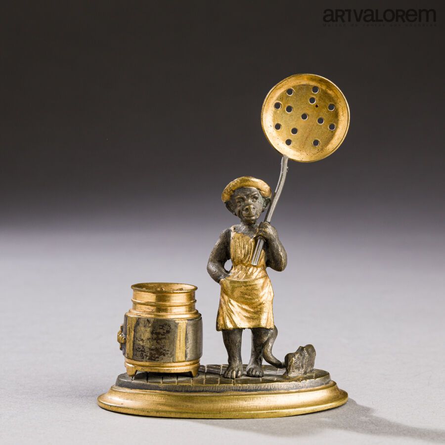 Null 一件镀金和铜化的青铜主题，描绘了一个猴子厨师拿着一个煎锅，站在炉子旁边，可能是为了收集吸油烟粉。搁置在一个椭圆形的底座上。 
19世纪末，20世纪初。&hellip;