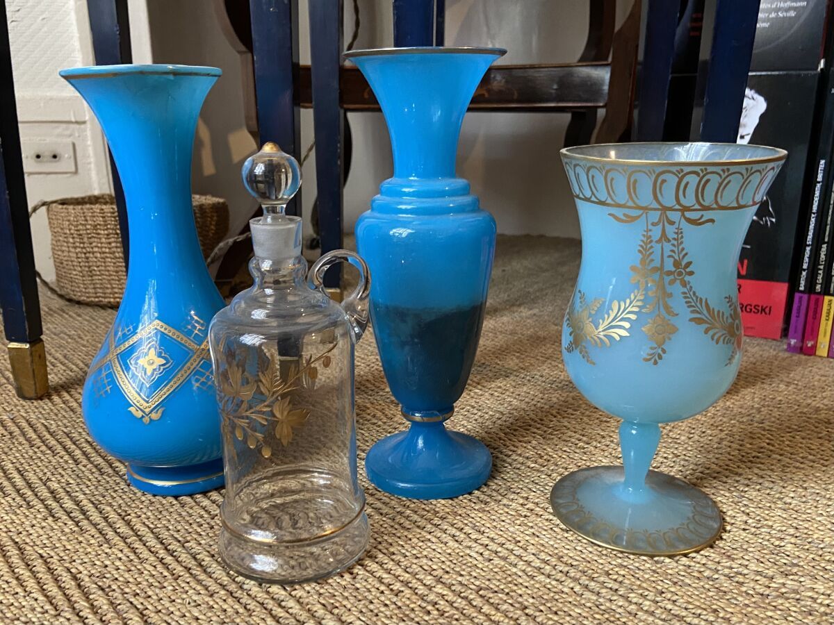 Null 一套玻璃器皿，19世纪，包括：无色玻璃镀金装饰的单柄瓶和瓶塞，以及三个蓝色乳白玻璃镀金装饰的花瓶（事故和修复）。 
H.22至26厘米