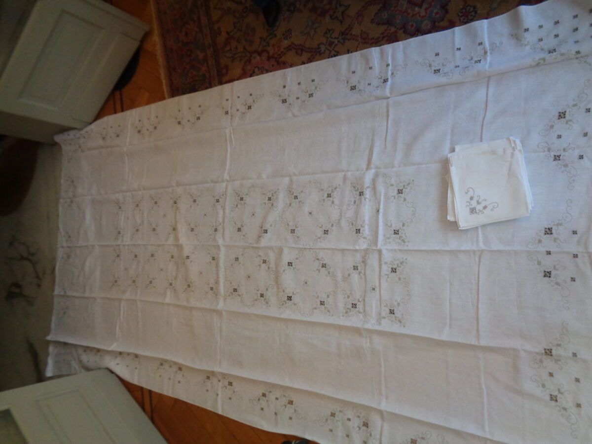 Null 桌布和十二张餐巾，下摆缝制，绣有阿拉伯式卷轴的灰色图案。
2.90 x 1.62 米