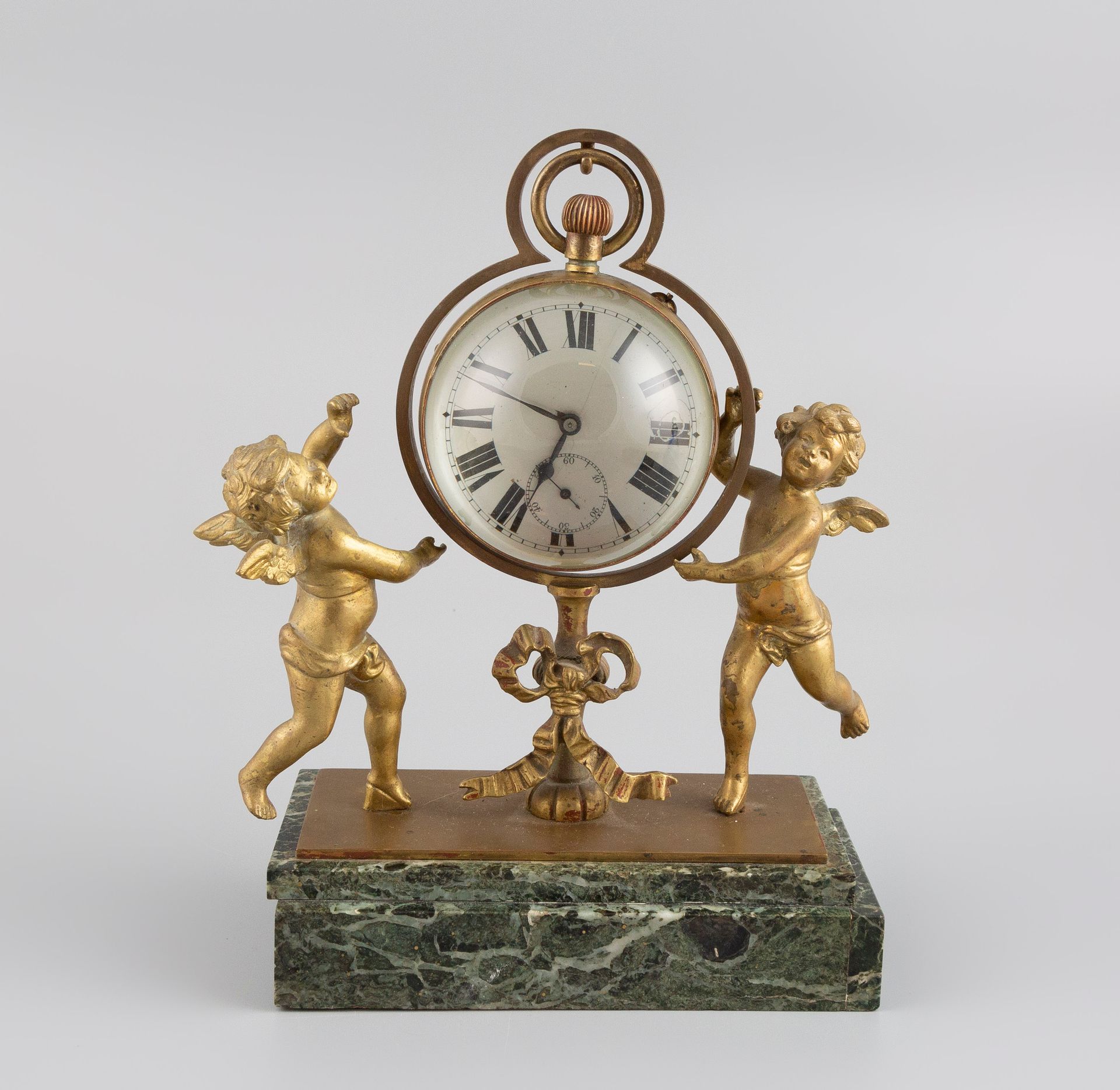 Null Pendule loupe en bronze et marbre à décor d'amours. H.22cm.