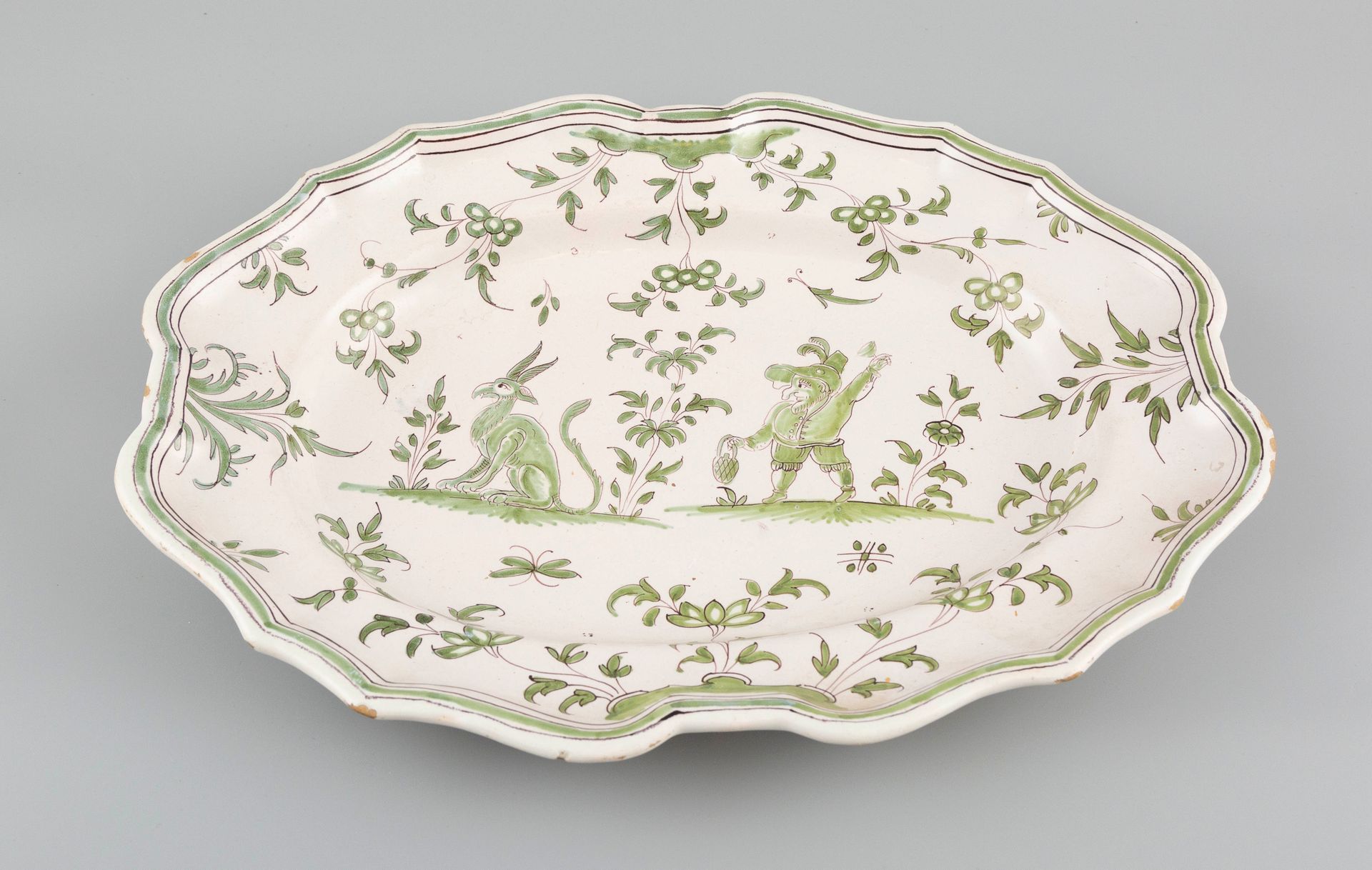 Null Moustier（18世纪）。长方形的陶器盘子，上面装饰着一个怪人。L36cmxl27cm。