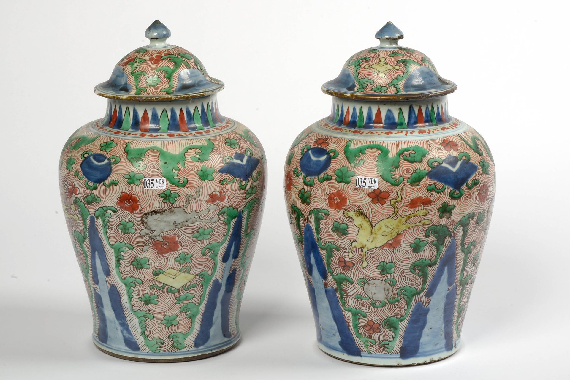 Null 一对 "五彩 "珐琅彩的中国多色瓷盖花瓶，在铁红色的螺旋形背景上装饰着 "奔马 "和佛教纹样。中国的工作。年代：17世纪，过渡时期。(*和一个**)。&hellip;