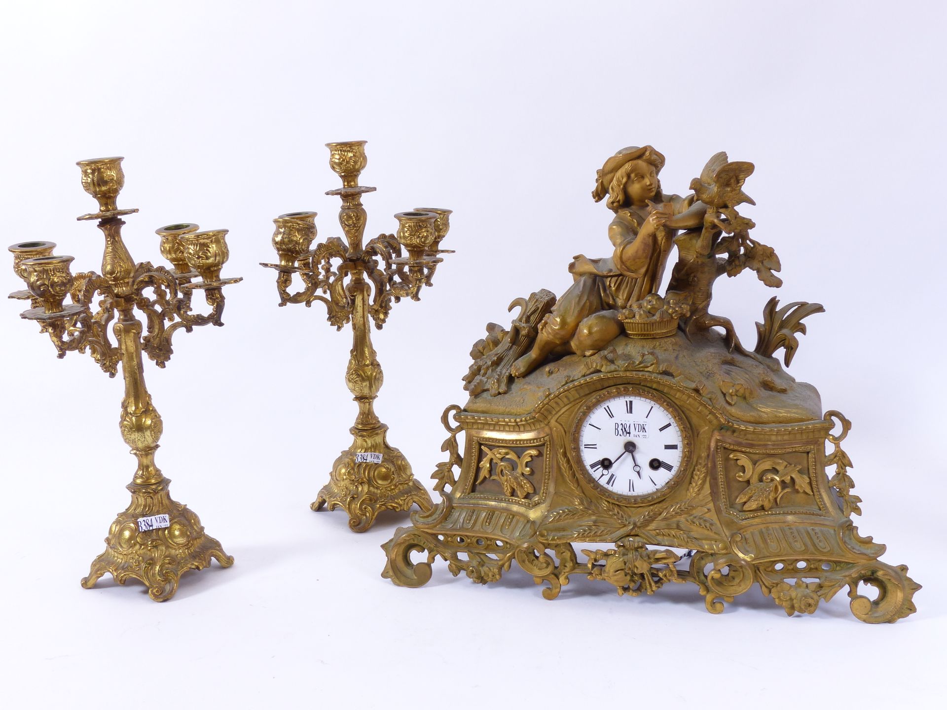Null 一个镀金的铜质时钟（高：34厘米）和一对铜质烛台（高：35厘米）。