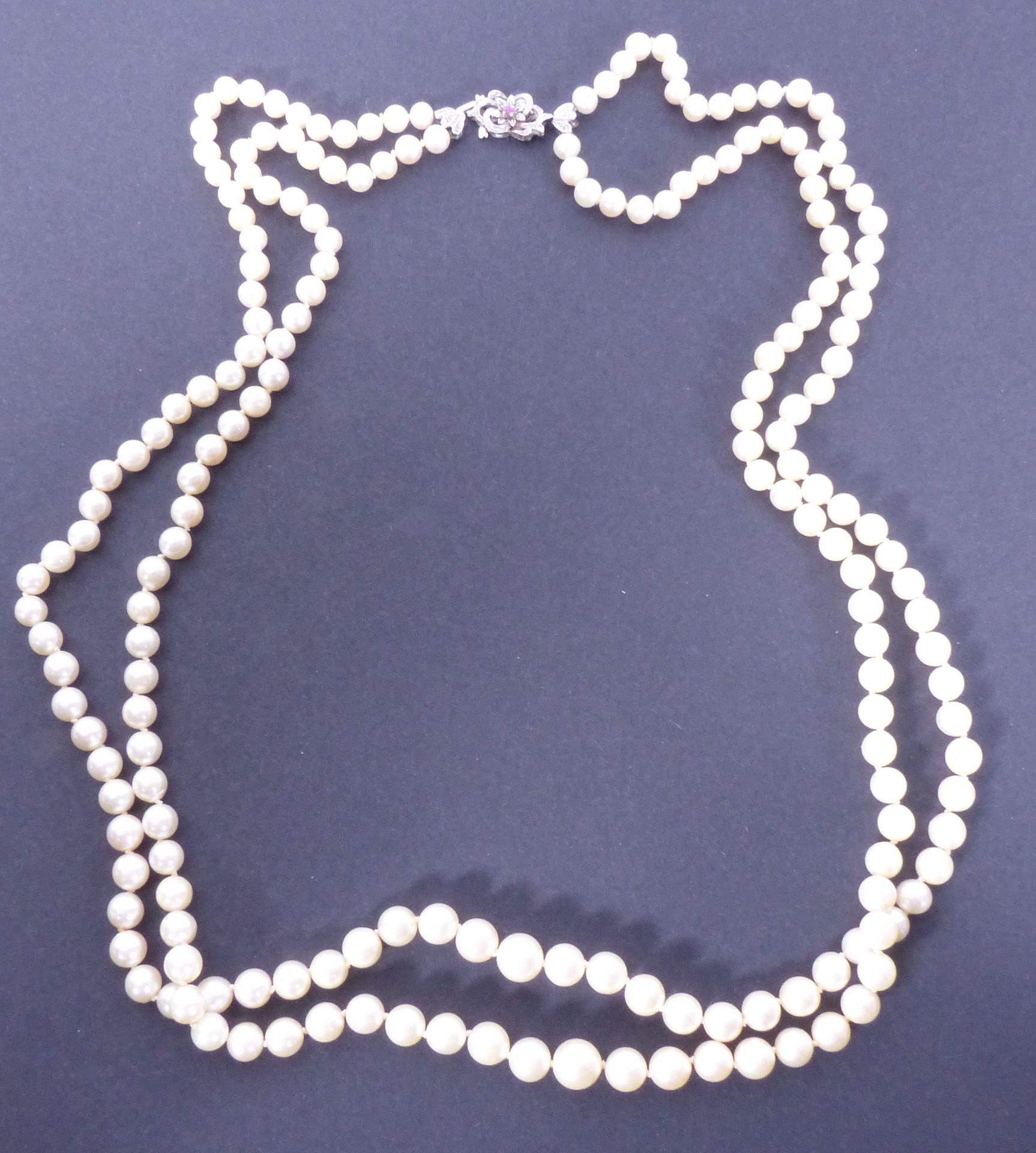 Null 项链有2排分级珍珠（直径：5.5和9毫米之间），18K白金扣，镶嵌着一颗粉色蓝宝石。长：+/-70厘米。